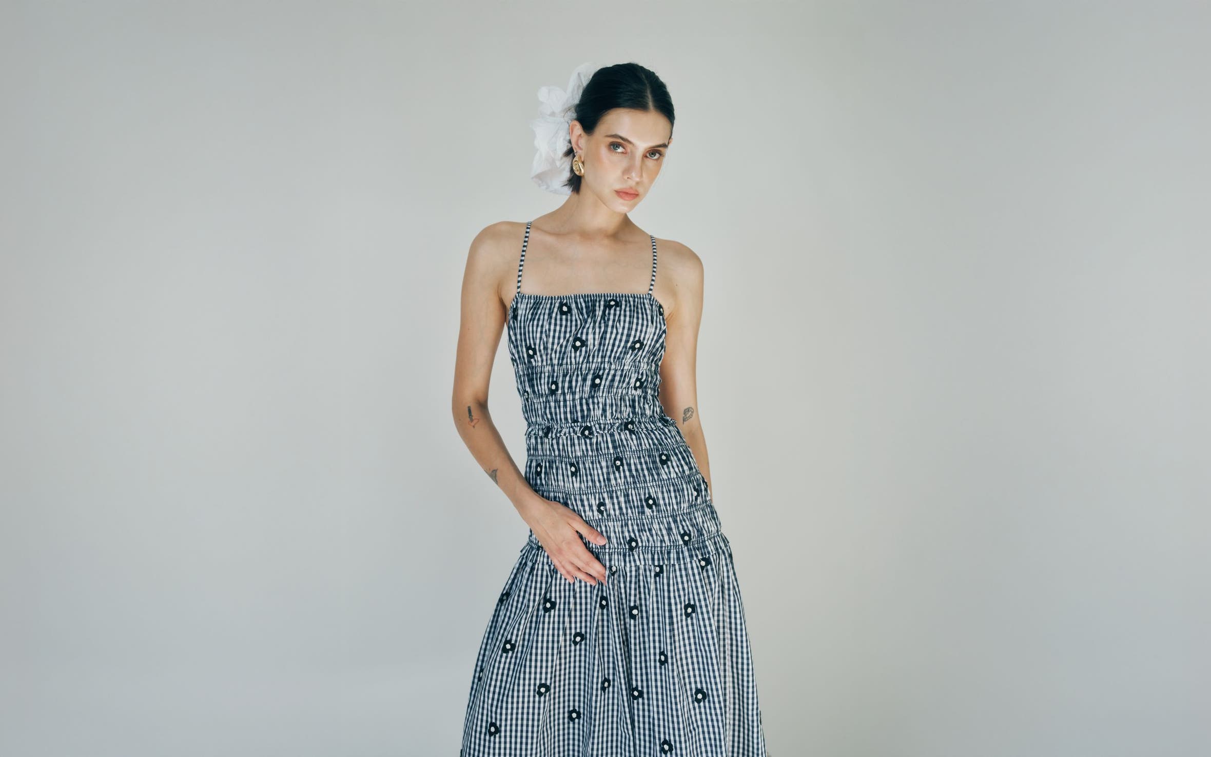 A woman wearing a checked smocked dress with embroidered daisies.
