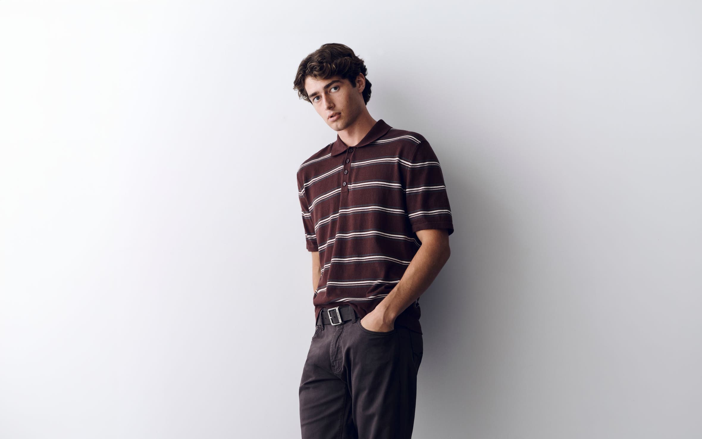 A man wearing Mavi Jeans and a striped polo. 