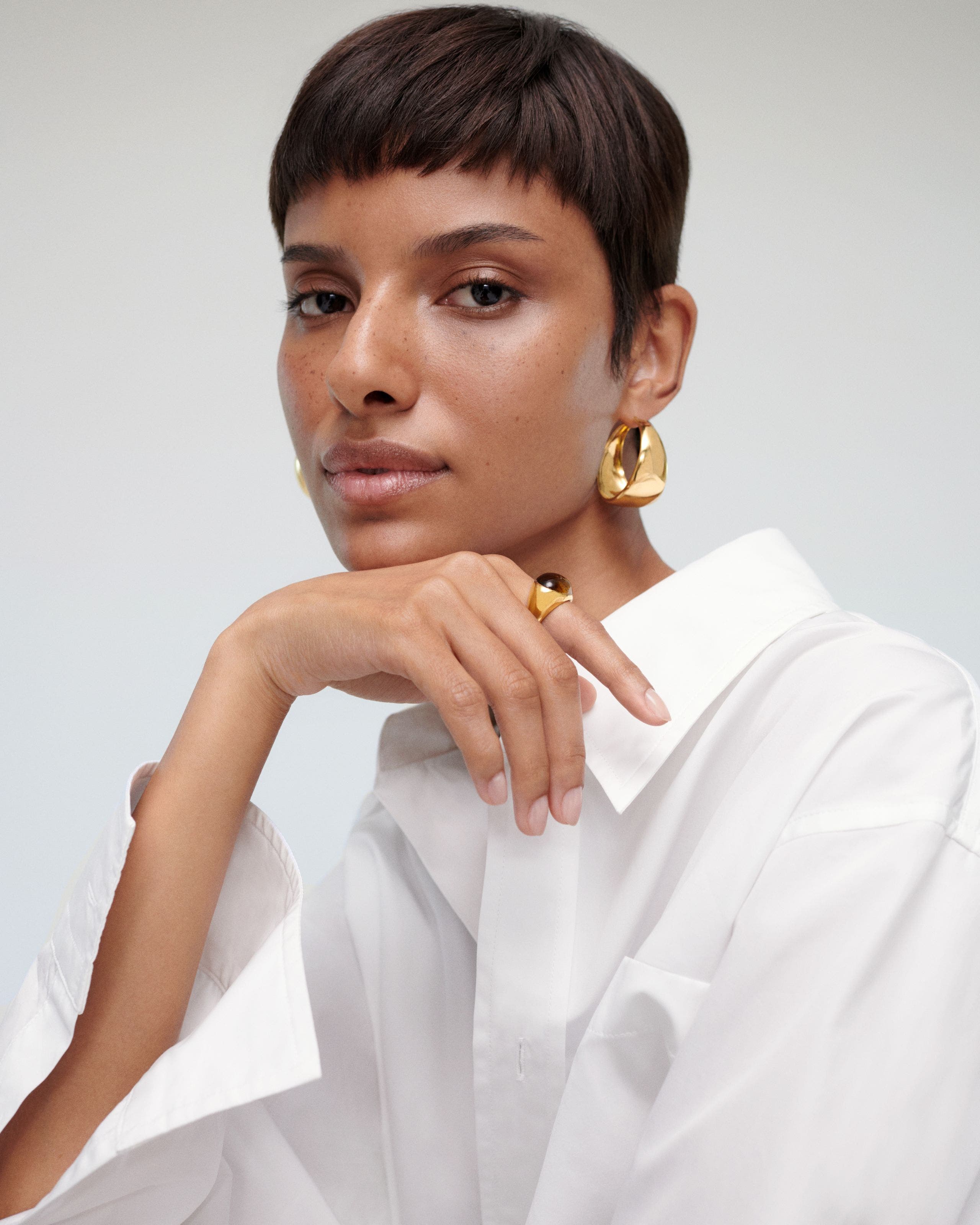 A woman wearing earrings and a ring.