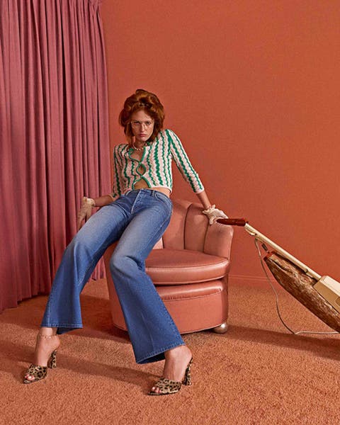 Woman wearing MOTHER flare denim and a green and white patterned top.