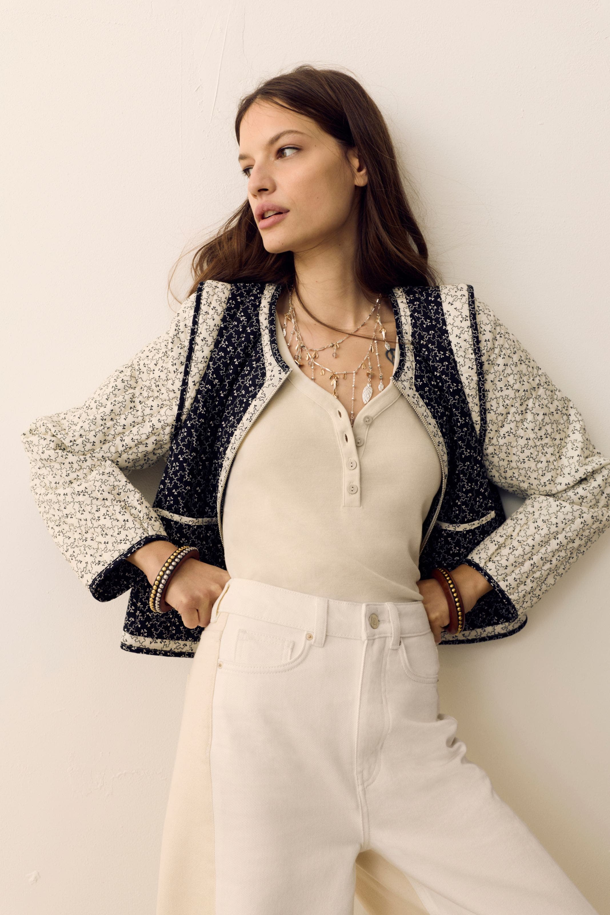 Woman wearing a printed jacket, henley shirt, white jeans and layered necklaces from Per Una.