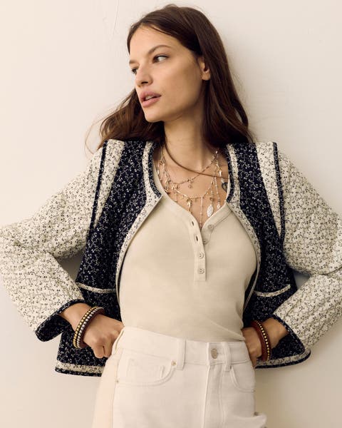 A woman wearing a Henley top and printed canvas jacket.