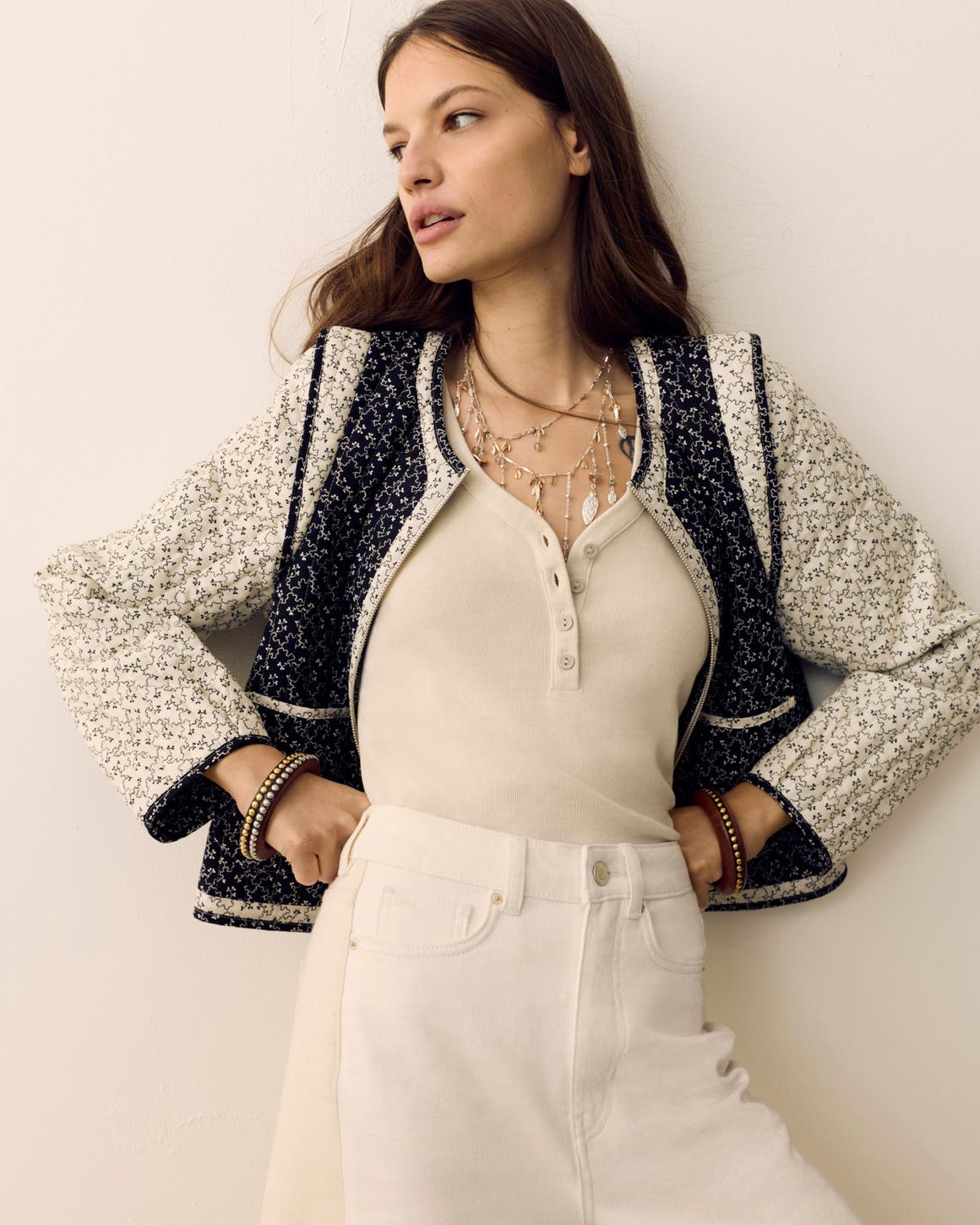 Woman wearing a printed jacket, henley shirt, white jeans and layered necklaces from Per Una.