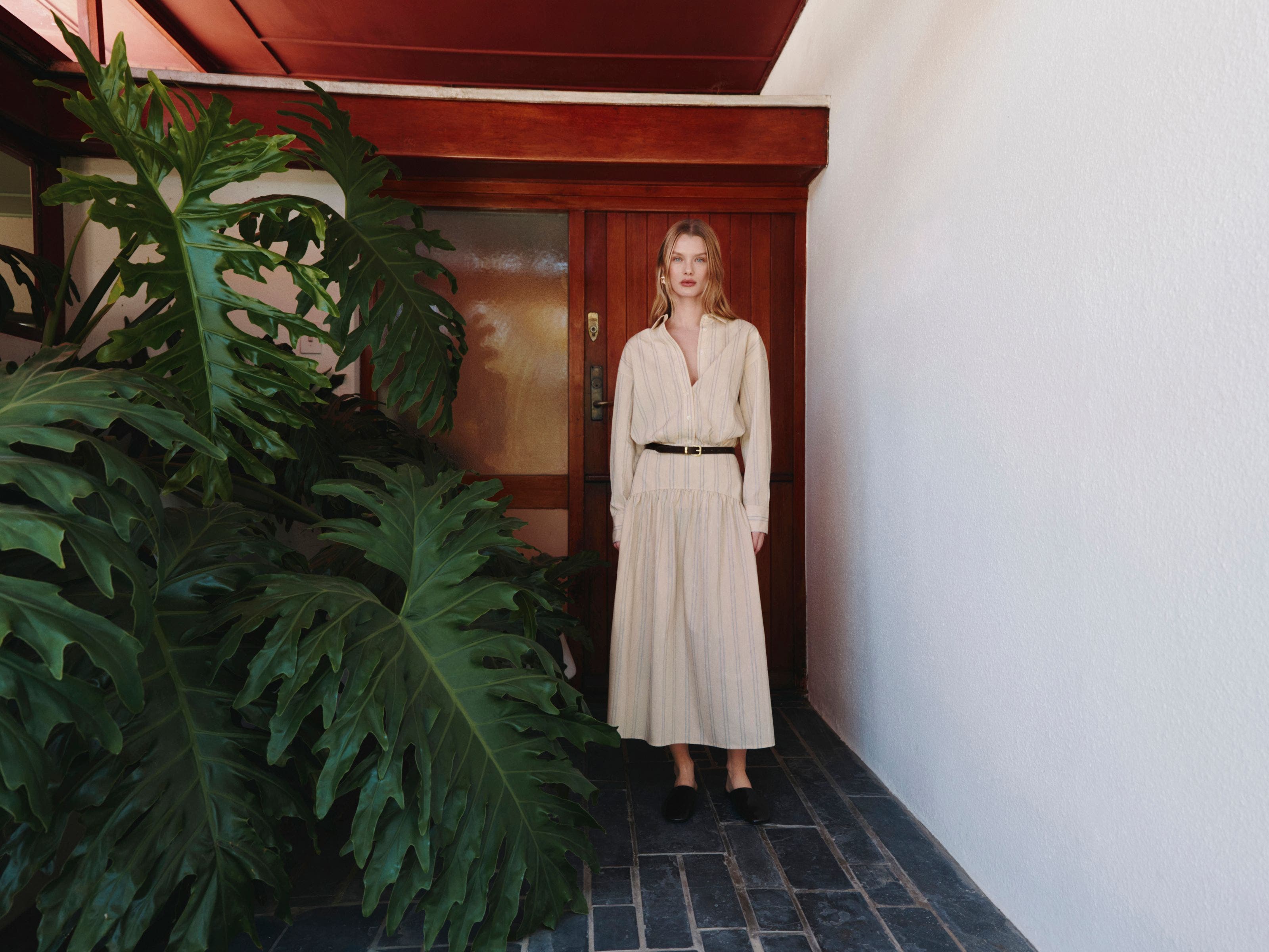 A woman wearing a striped shirtdress with a belt.