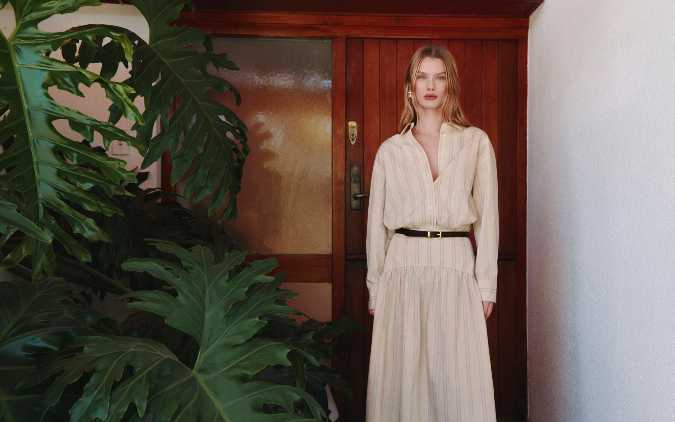 A woman wearing a striped shirtdress with a belt.