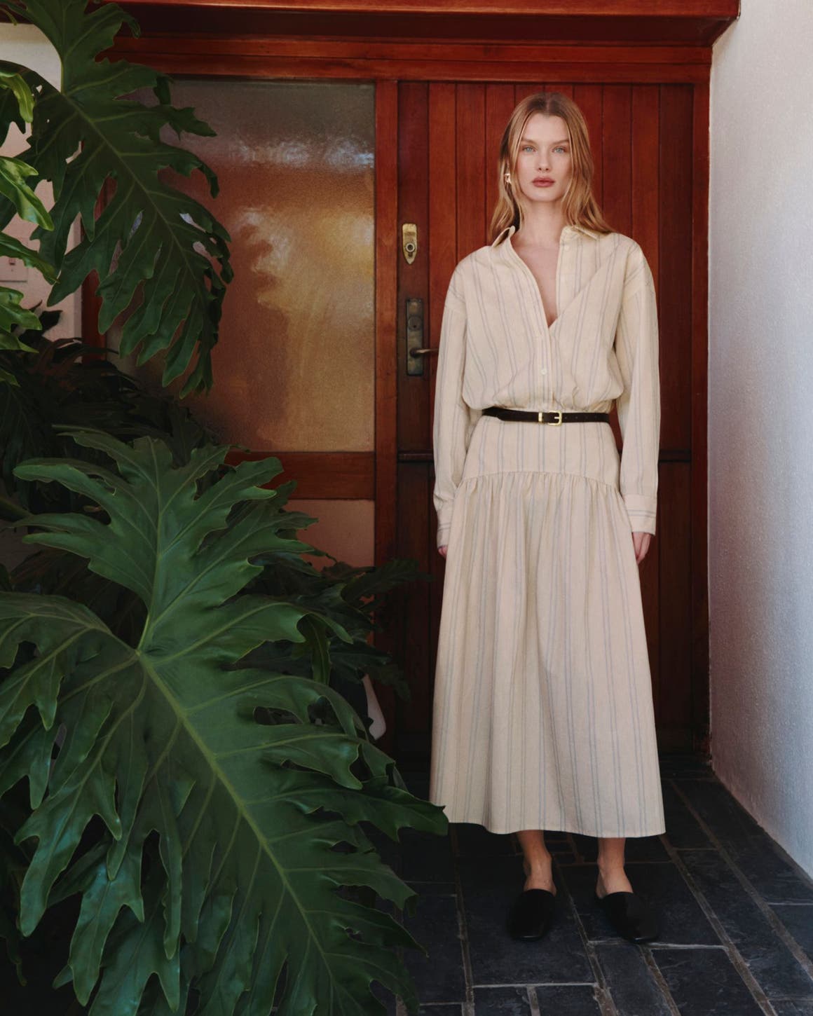 A woman wearing a striped shirtdress with a belt.