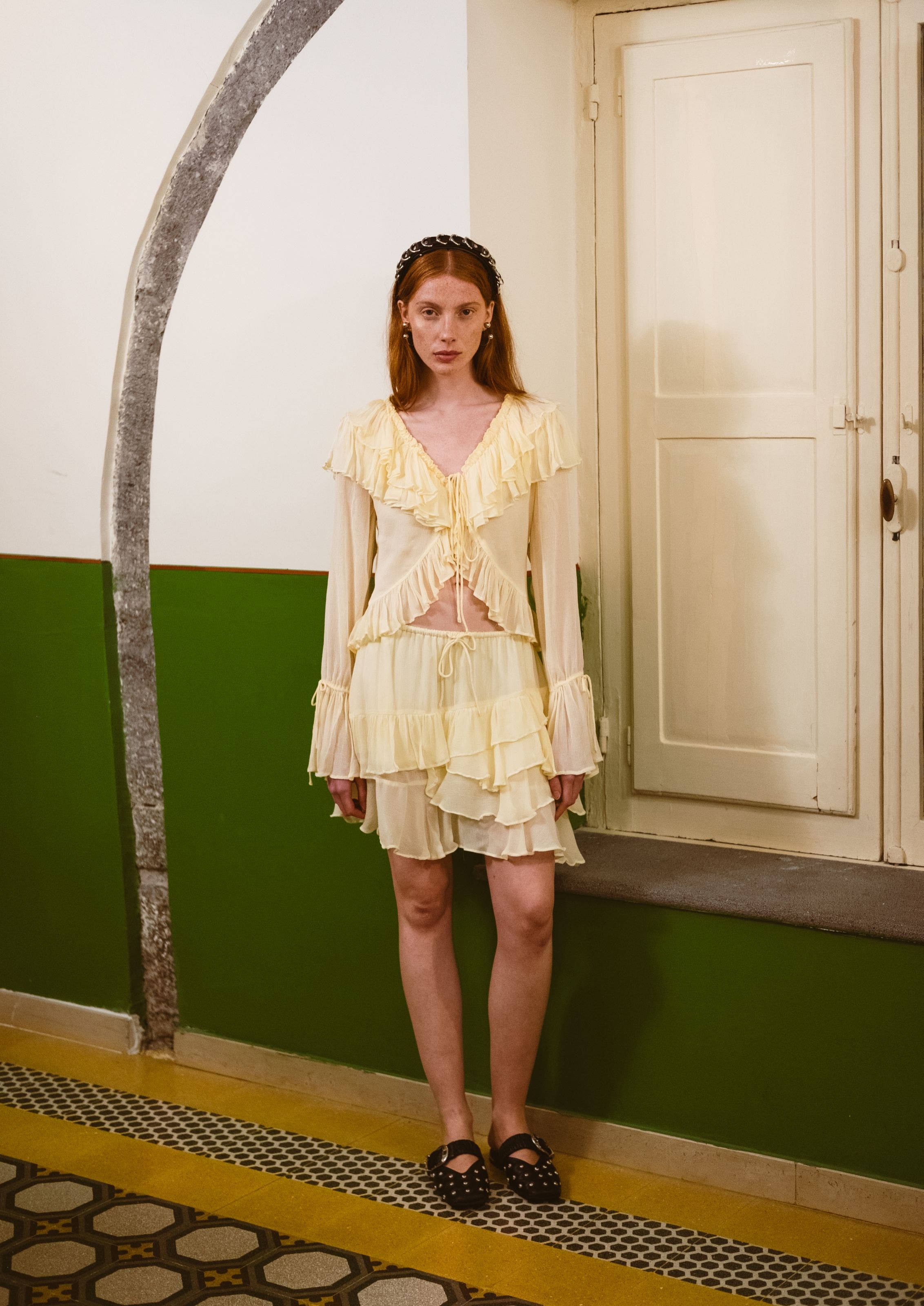 A woman wearing a light cream ruffled dress with long sleeves and a layered skirt.