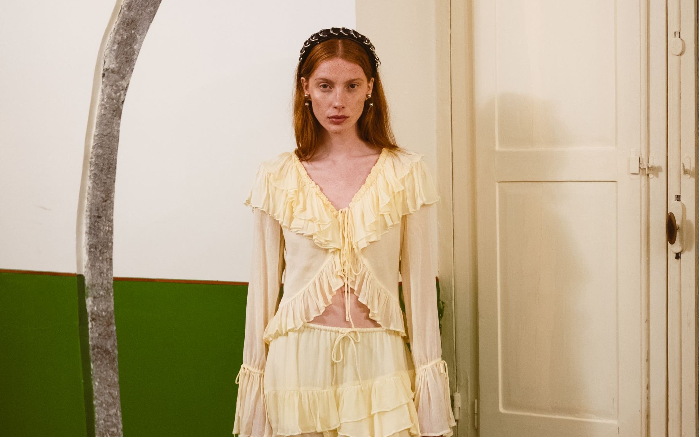 A woman wearing a light cream ruffled dress with long sleeves and a layered skirt.