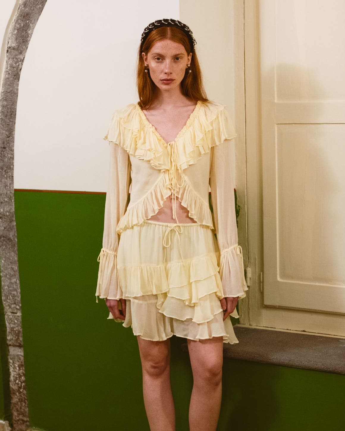 A woman wearing a light cream ruffled dress with long sleeves and a layered skirt.