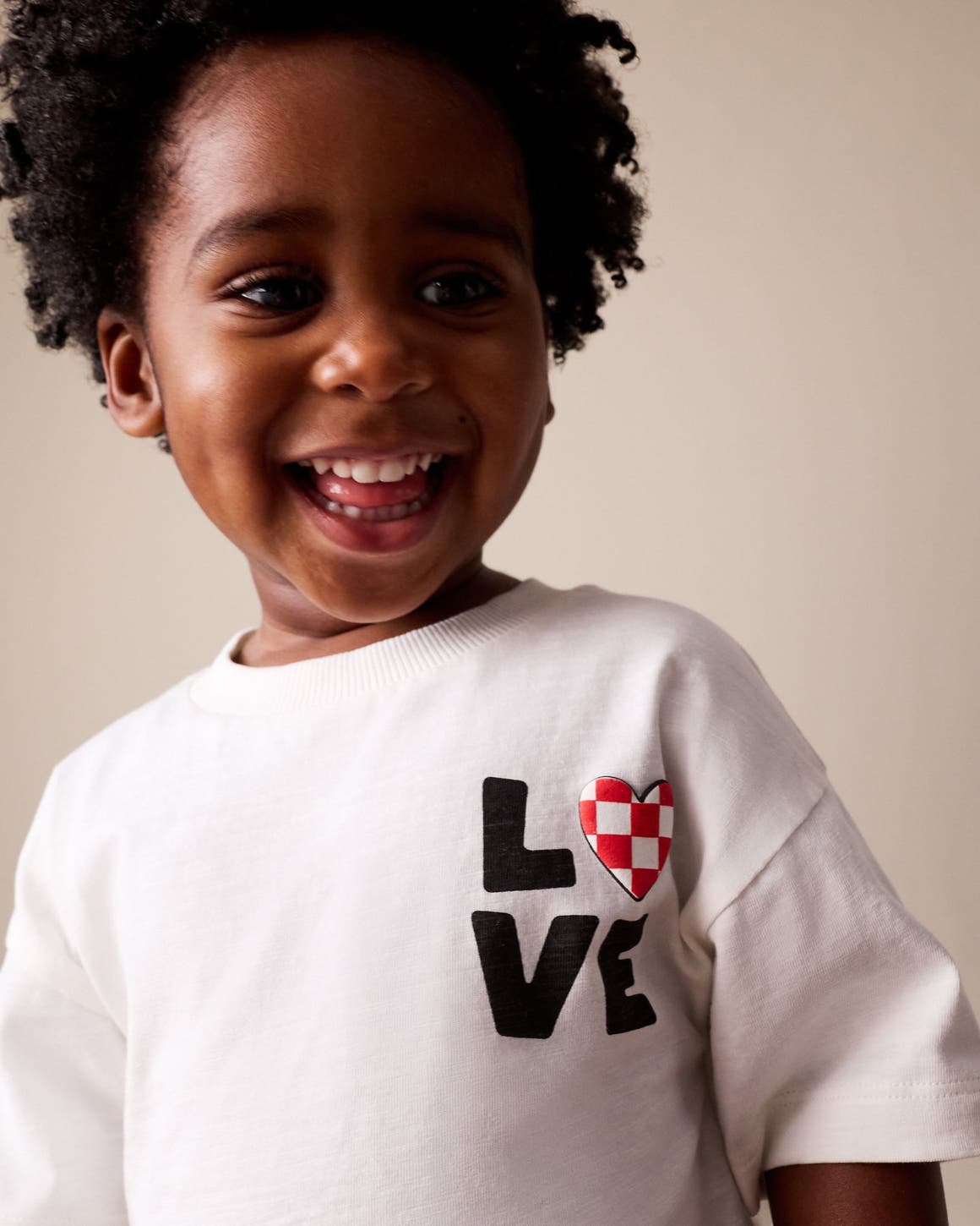 Little boy wearing a white t-shirt that says LOVE.