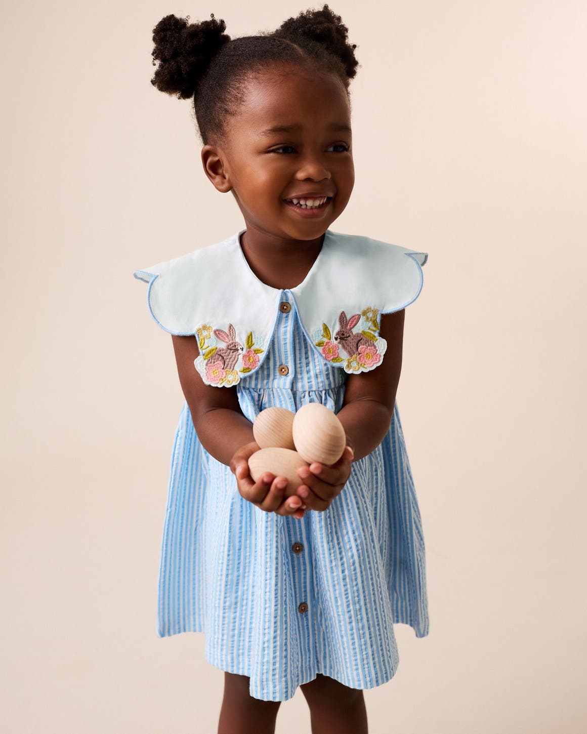 A little girl wearing a light blue dress with embroidered statement collar.