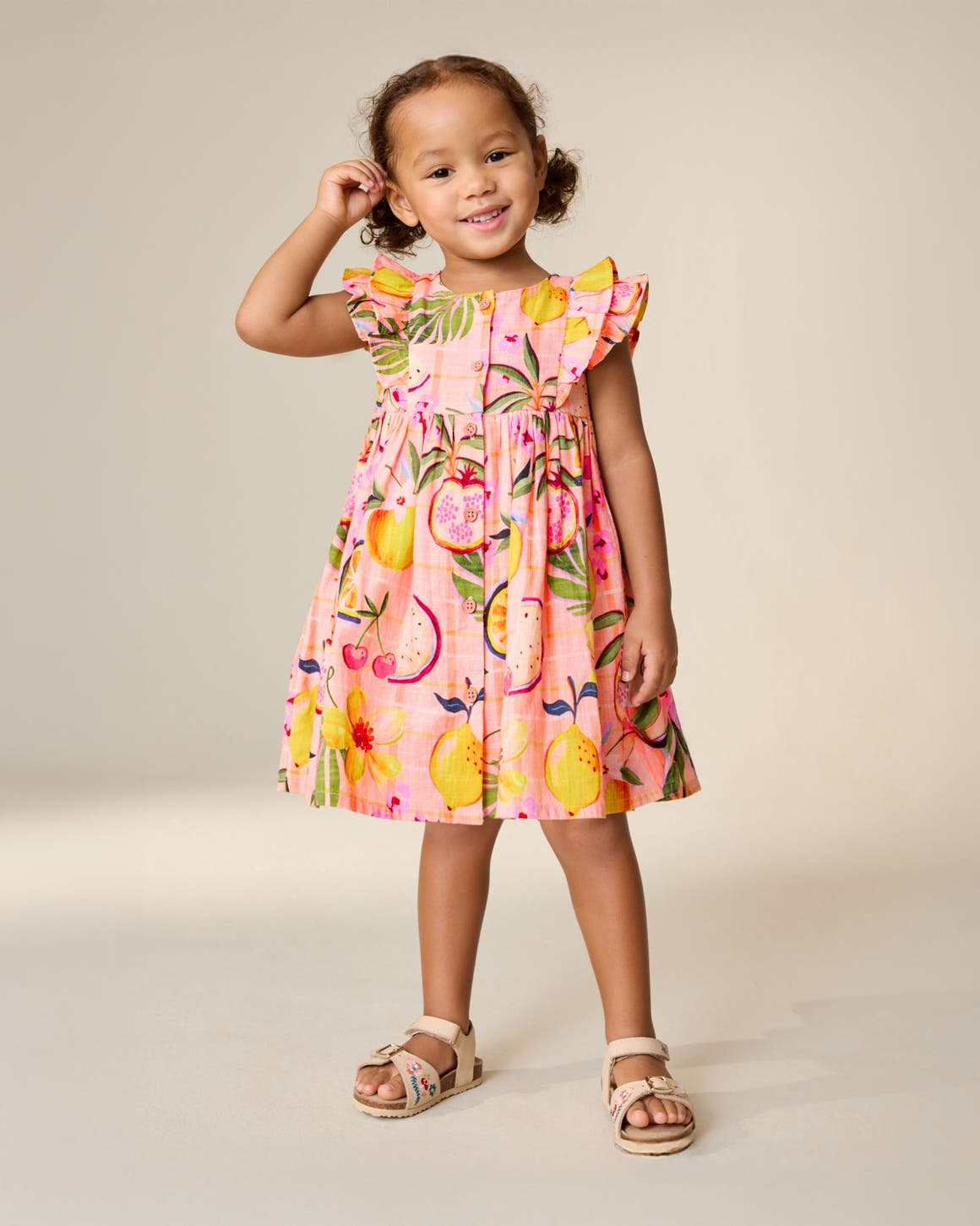 A little girl wearing a fruit-print sundress from Next.