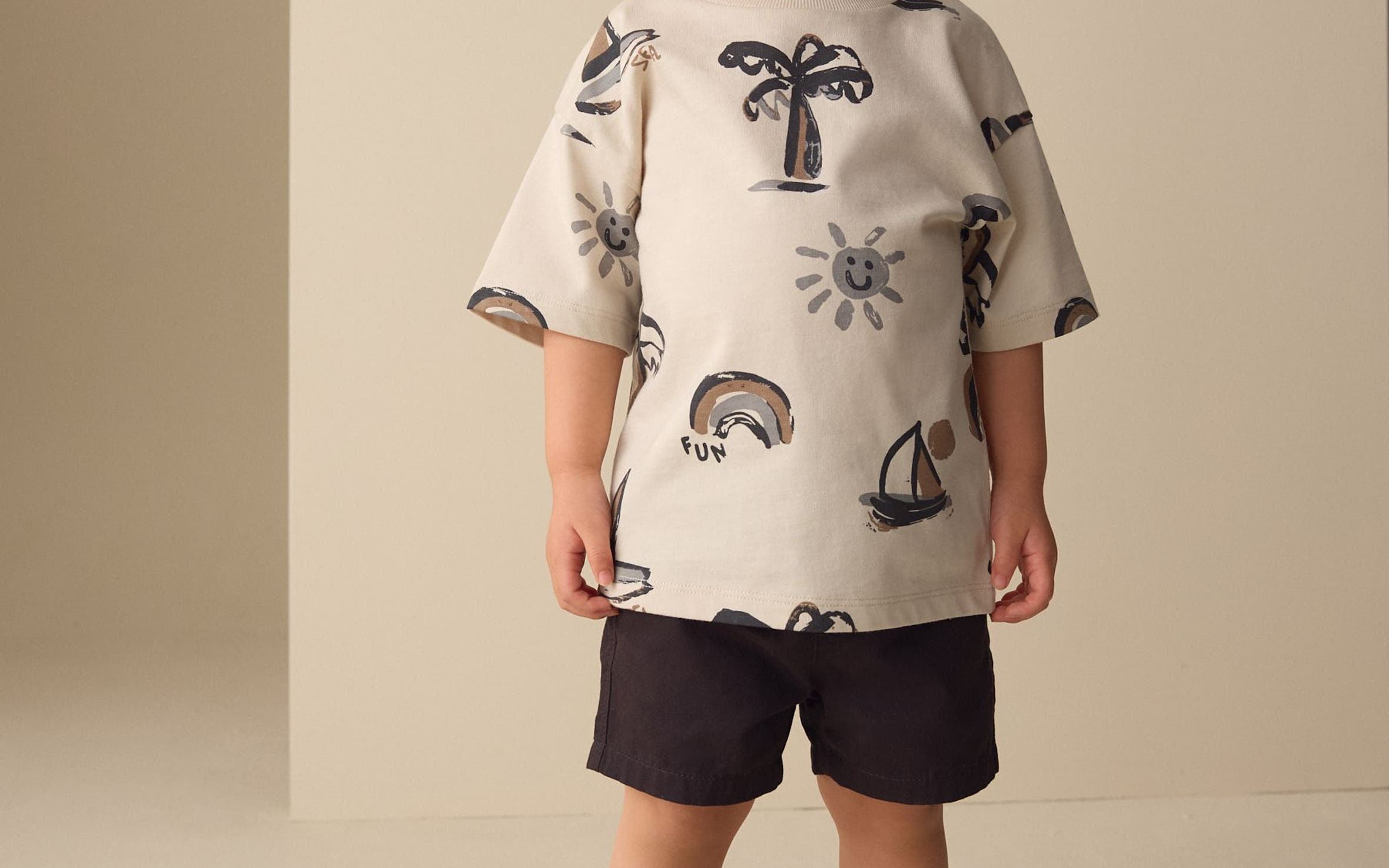 A boy wearing a summer-print T-shirt and shorts from Next.
