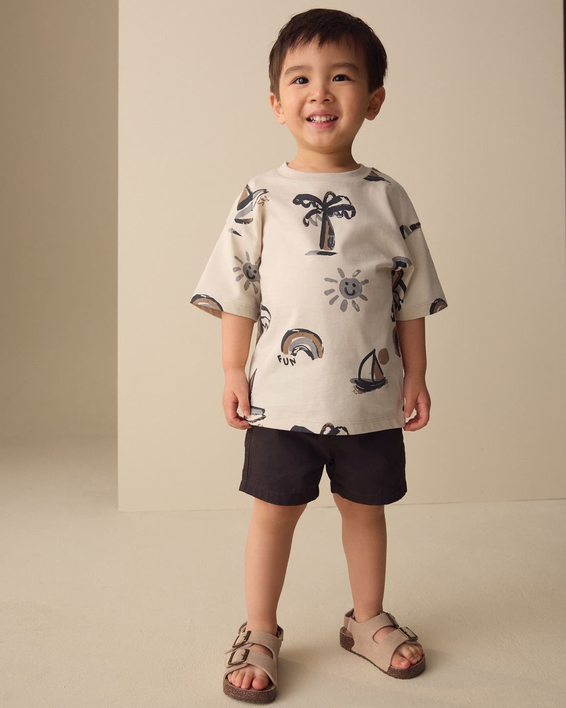 A boy wearing a summer-print T-shirt and shorts from Next.