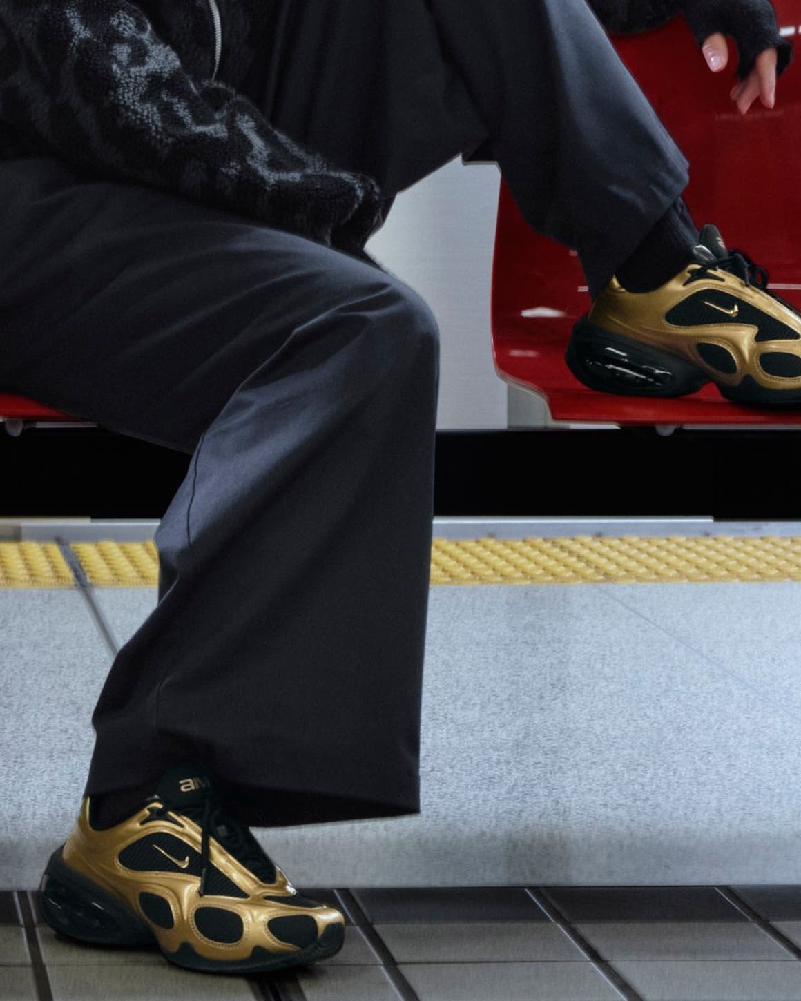Two models wearing Nike shoes sitting on a bench