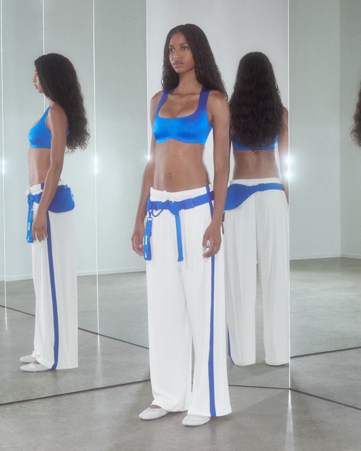 A woman wearing a sports bra and track pants.