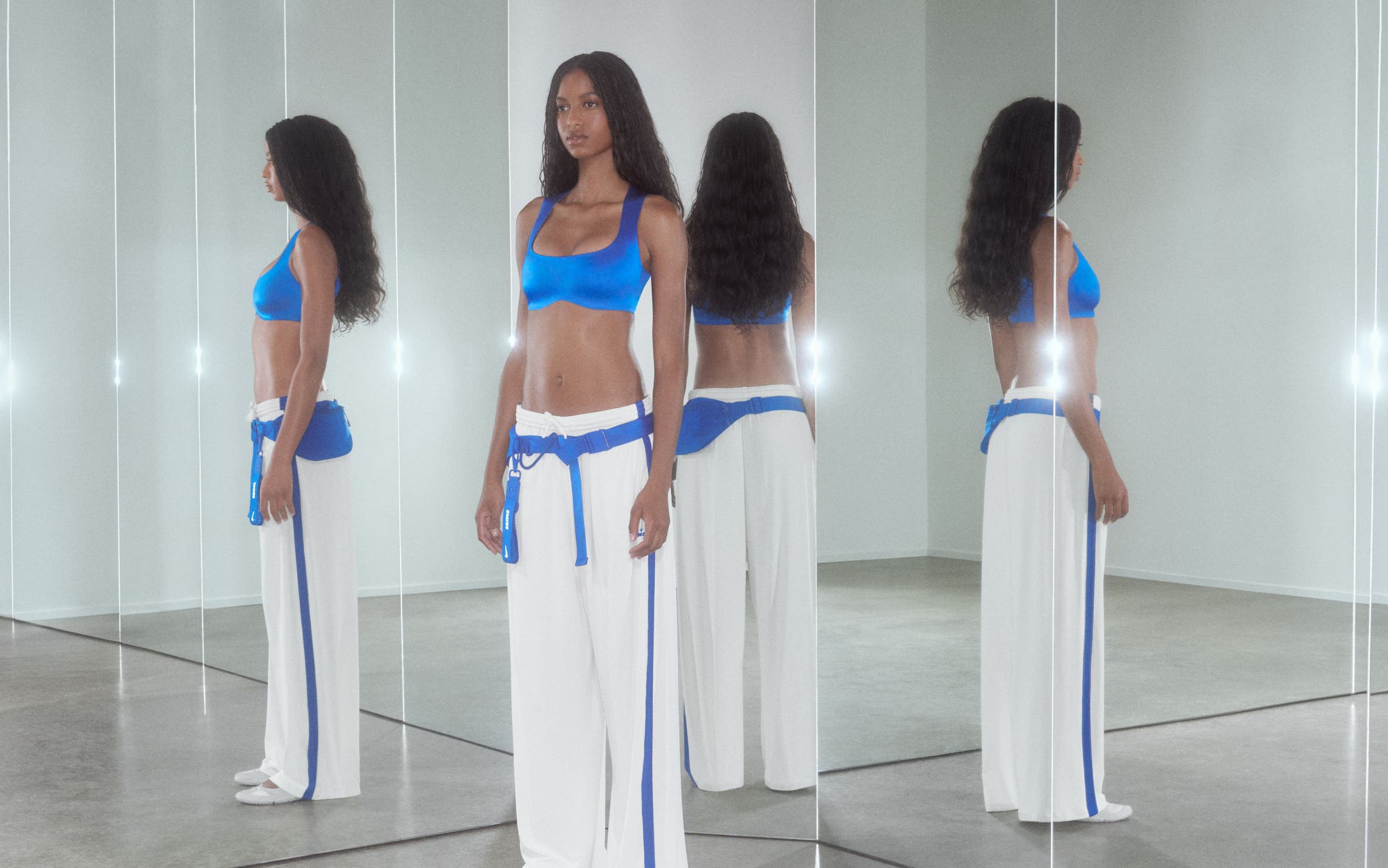 A woman wearing a sports bra and track pants.