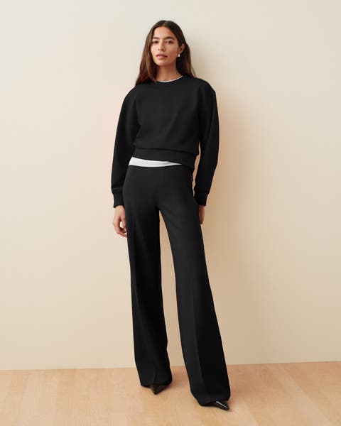 Woman wearing a black SPANX crewneck and pants set.