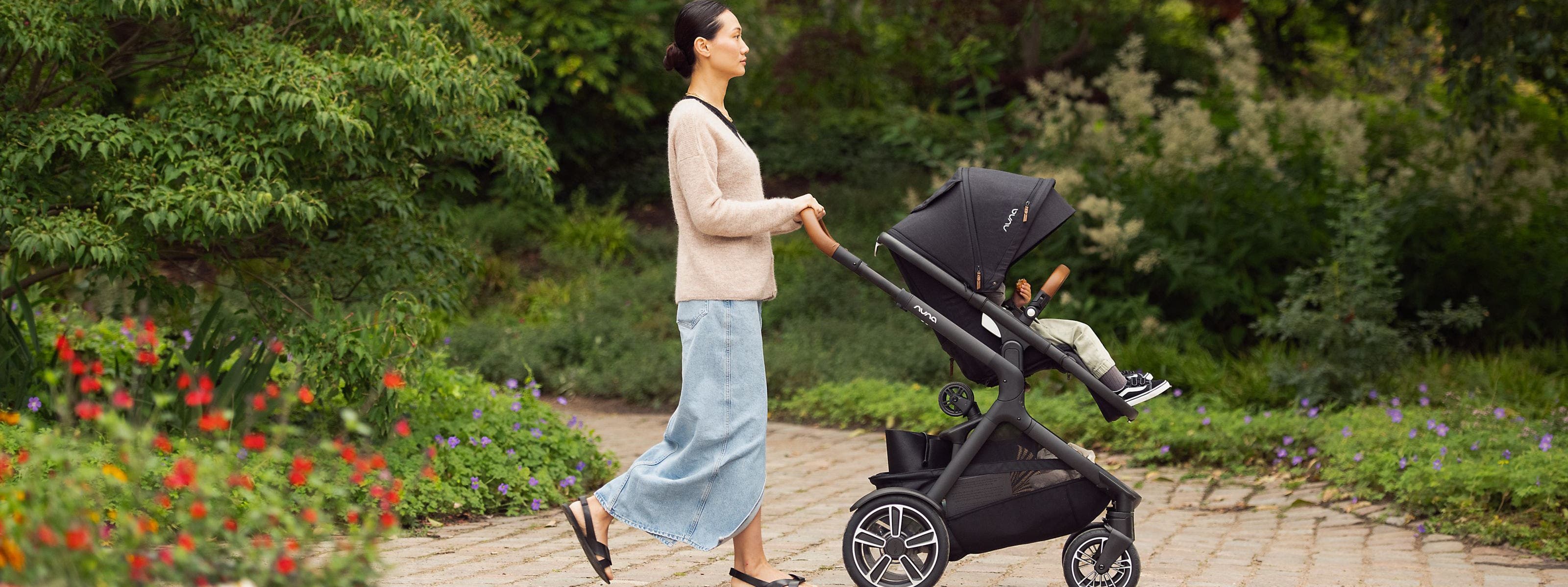 A woman pushing a child in a Nuna stroller.