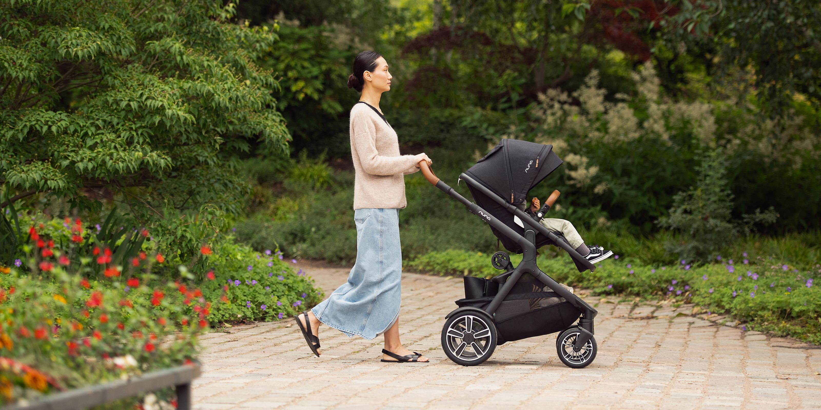 A woman pushing a child in a Nuna stroller.