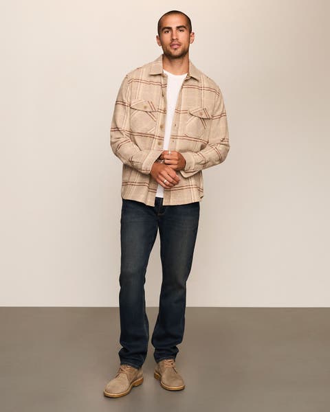 Man wearing tan plaid open button up and dark denim jeans