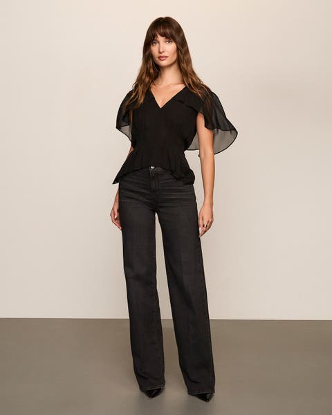 Woman wearing a black flowy blouse and dark jeans