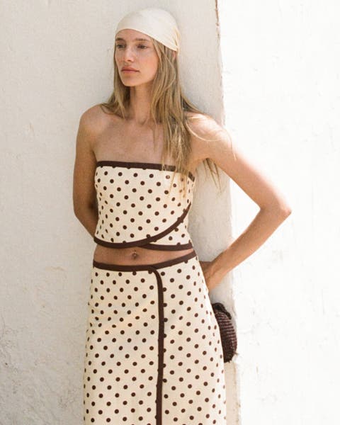 A woman wearing a polka dot crop top and matching midi skirt.