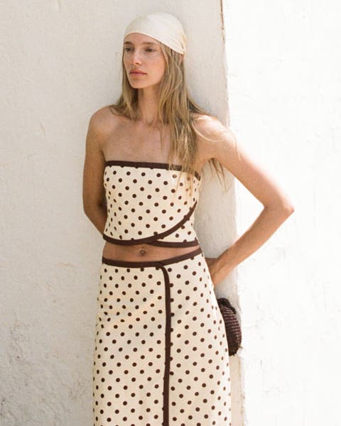 A woman wearing a matching polka dot midi skirt and crop top.