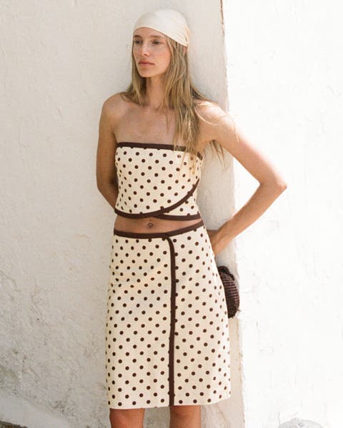 A woman wearing a polka dot crop top and matching midi skirt.