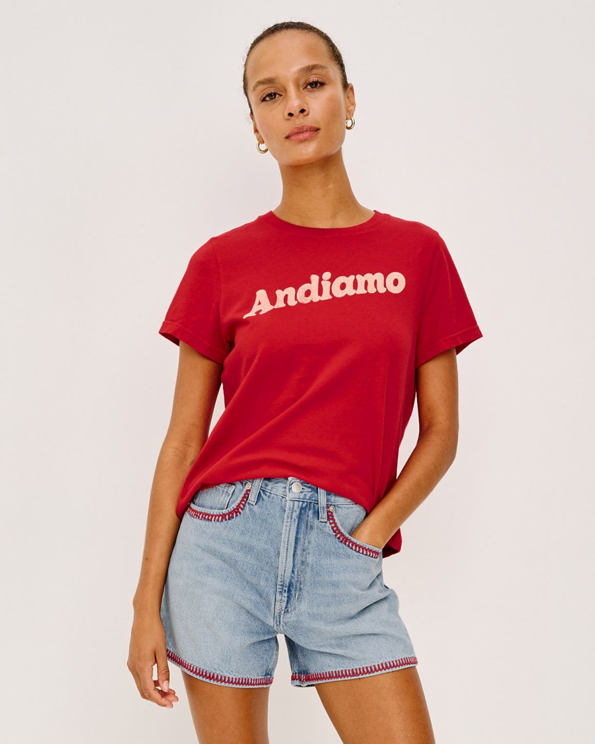 A woman wearing a graphic t-shirt and embellished denim shorts.