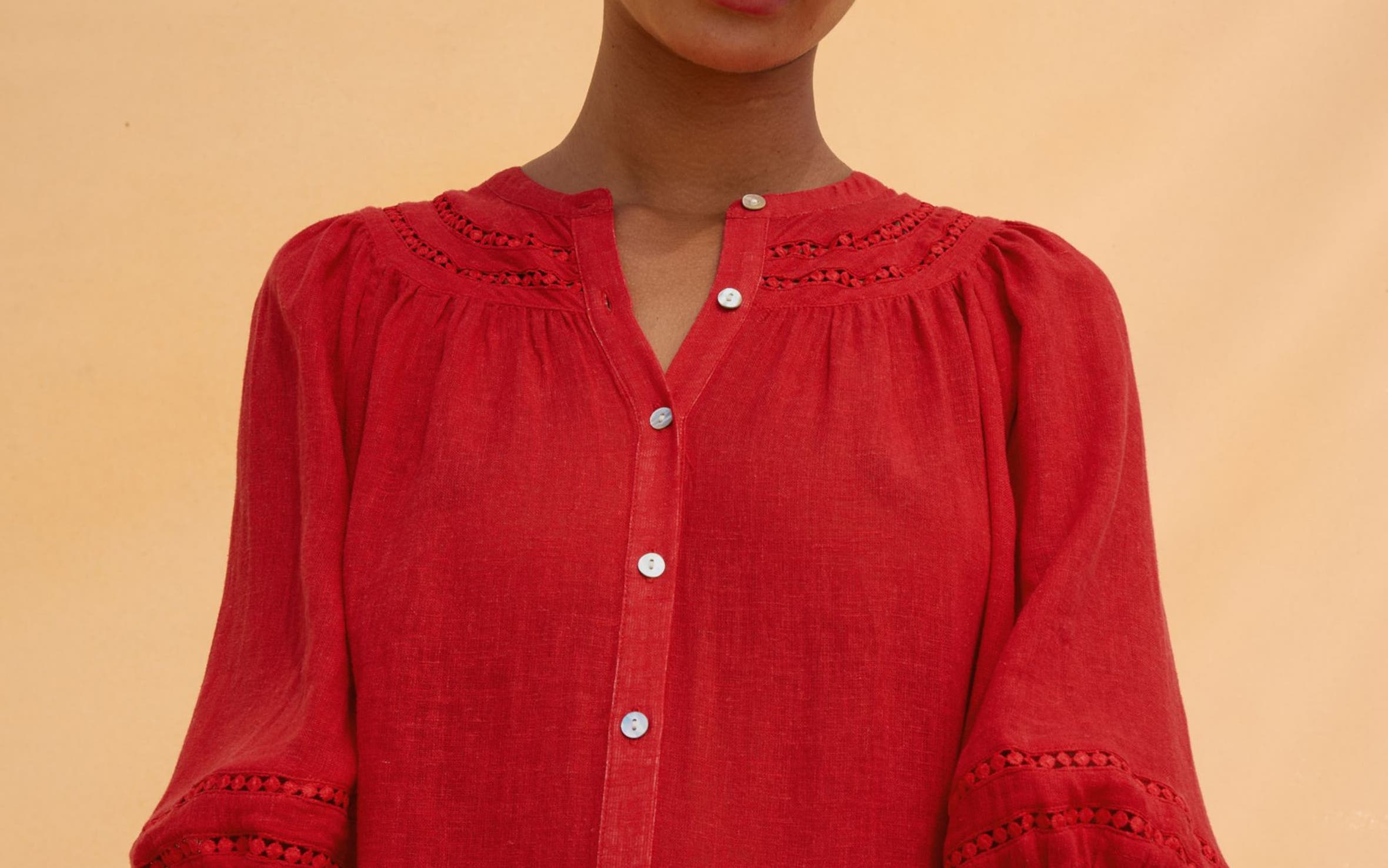 A woman wearing a gingham head scarf and red top carrying tomatoes.