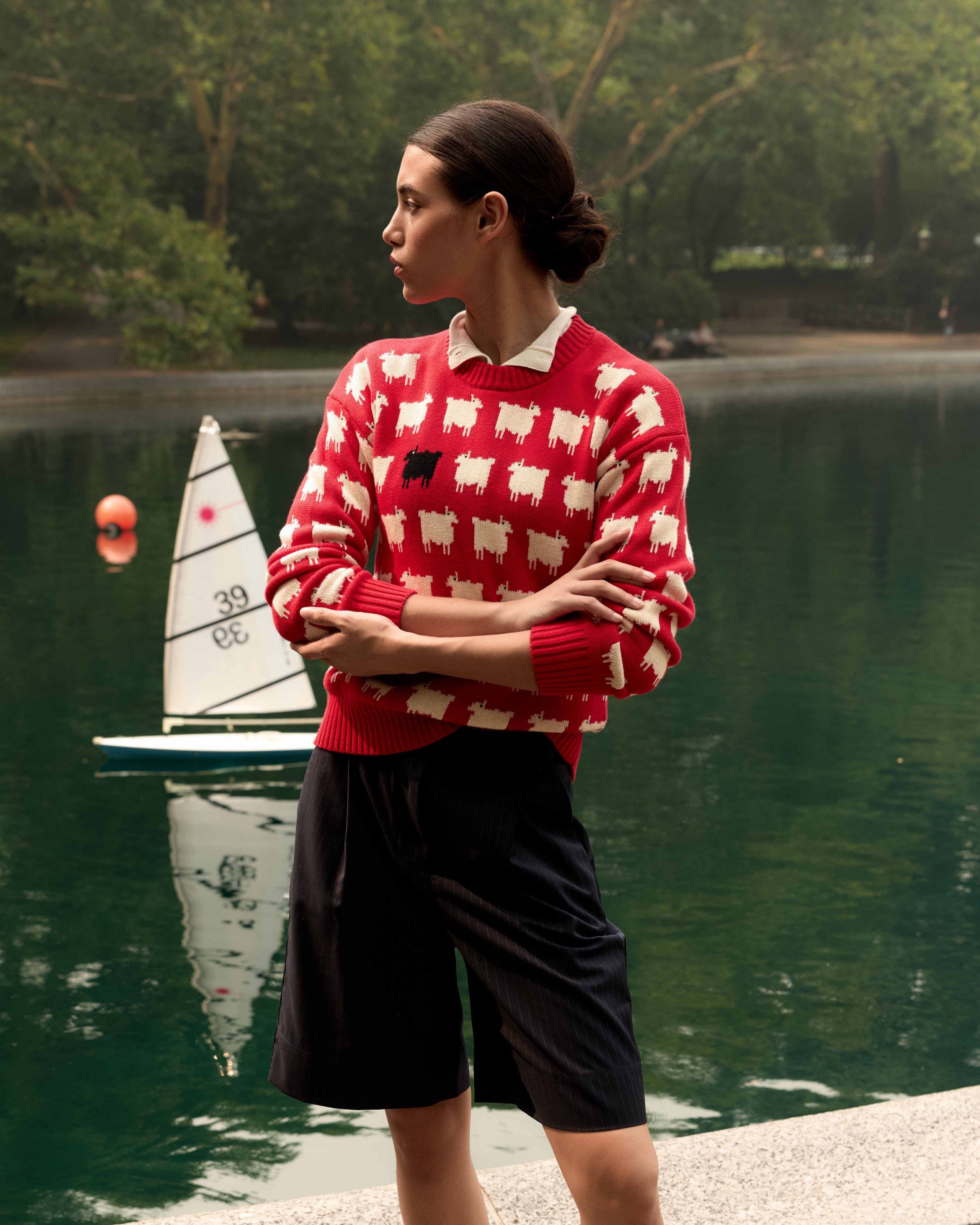 A woman wearing a red printed sweater and tailored shorts.