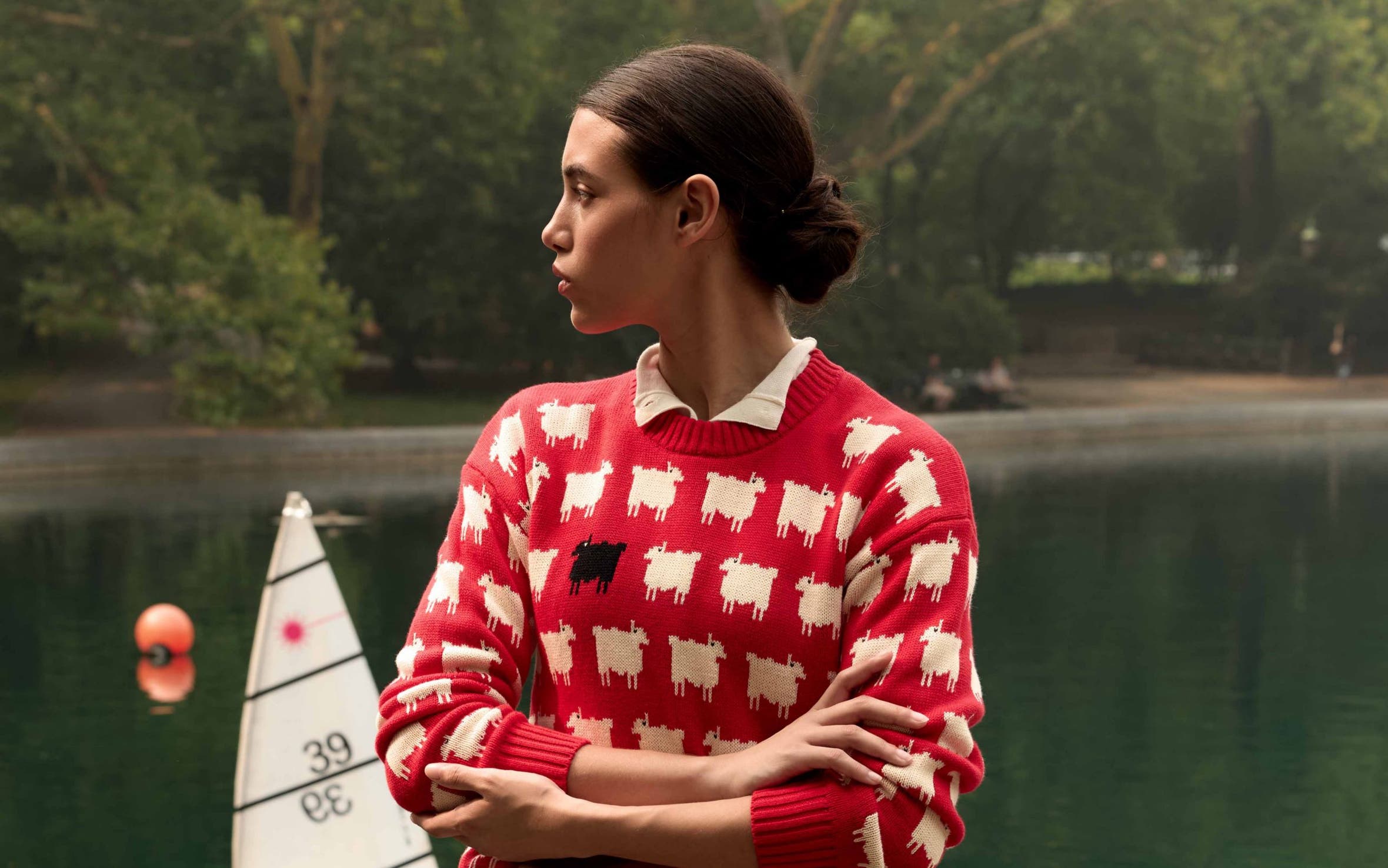 A woman wearing a red printed sweater and tailored shorts.