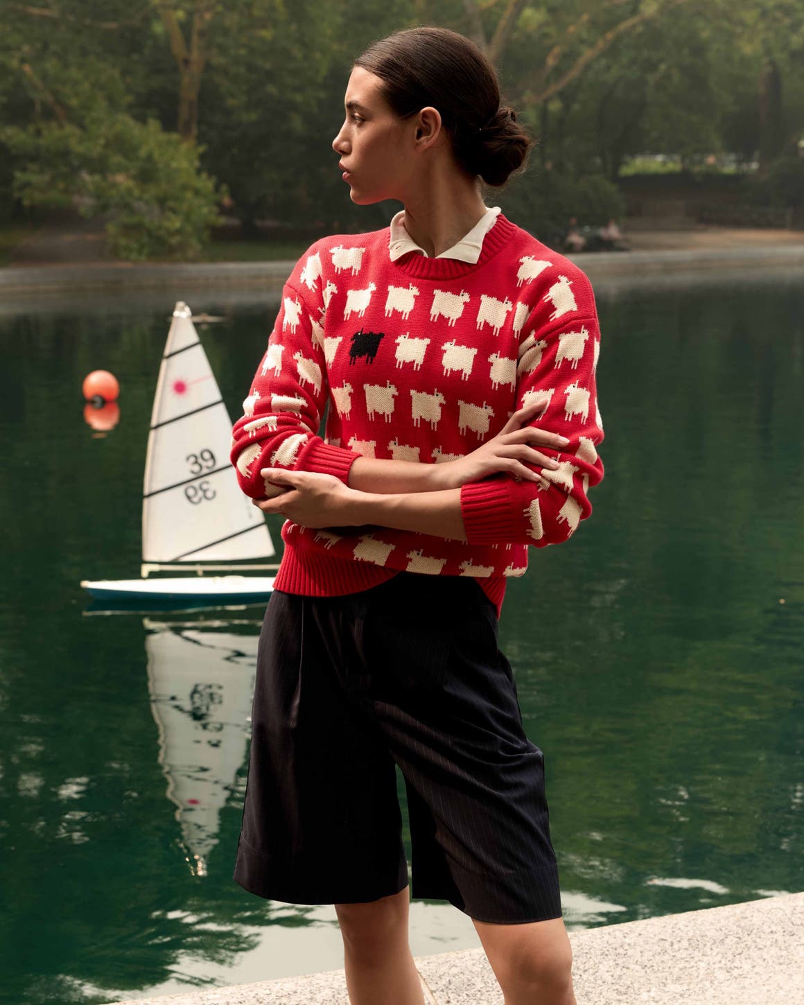 A woman wearing a red printed sweater and tailored shorts.