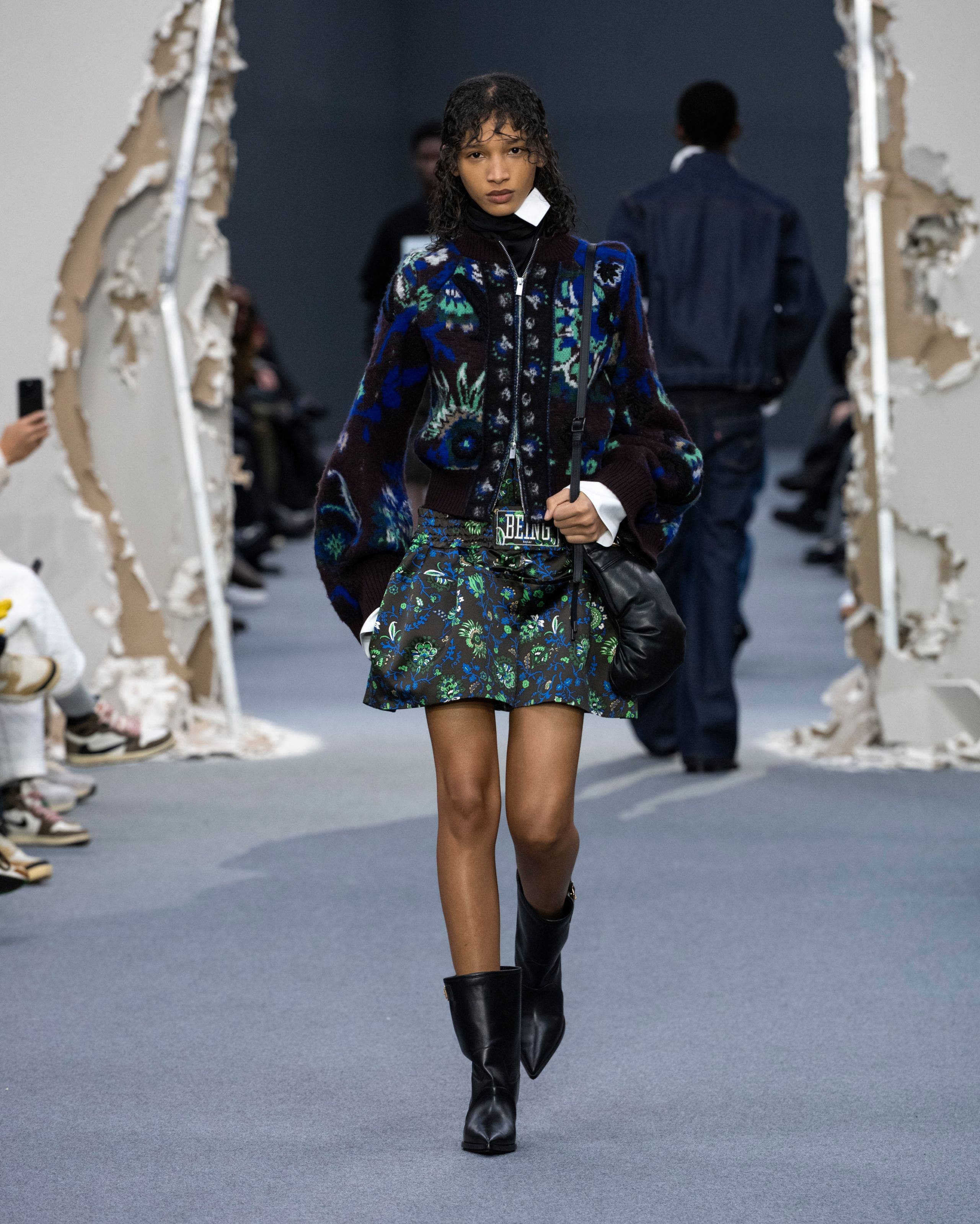 A woman in green floral dress with jacket.