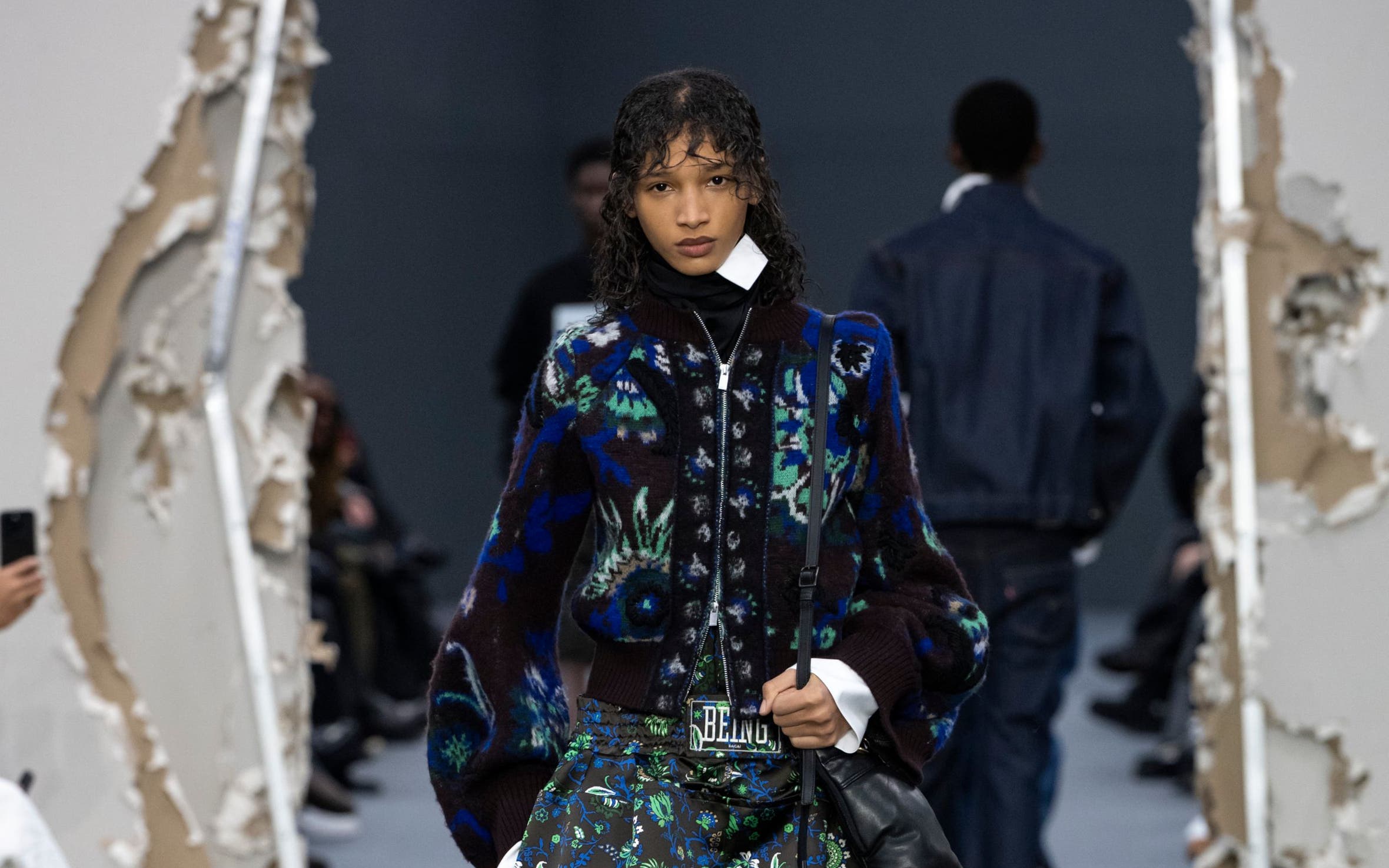 A woman in green floral dress with jacket.