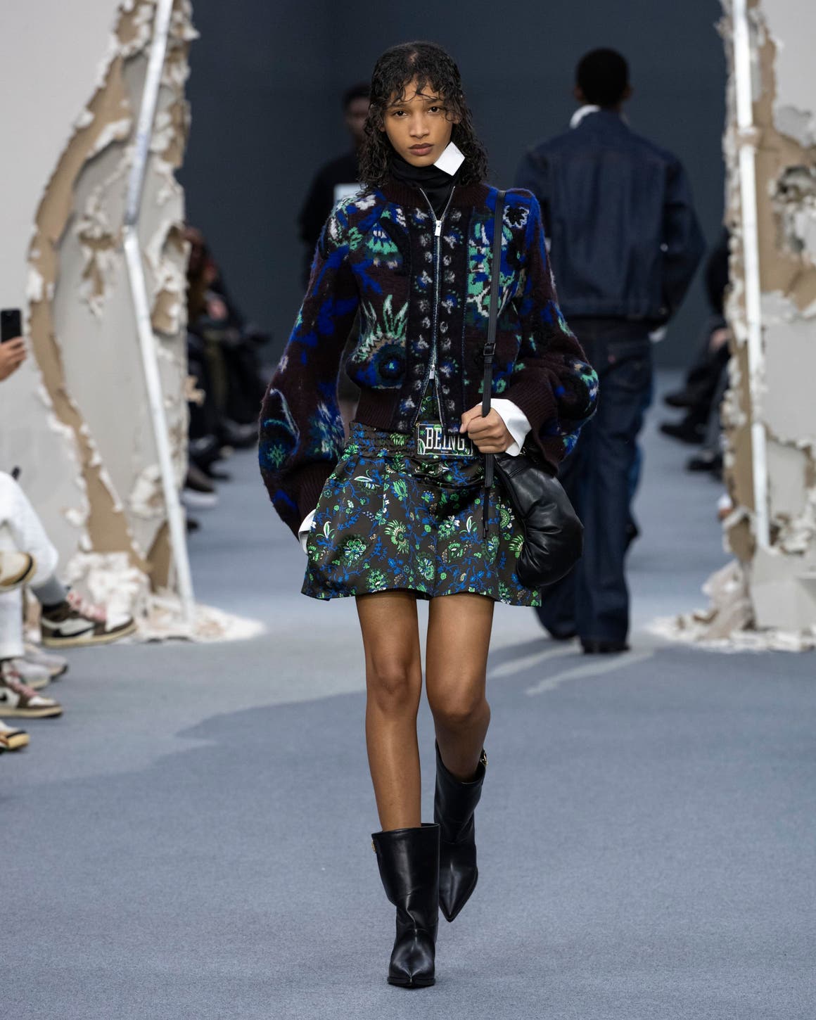 A woman in green floral dress with jacket.