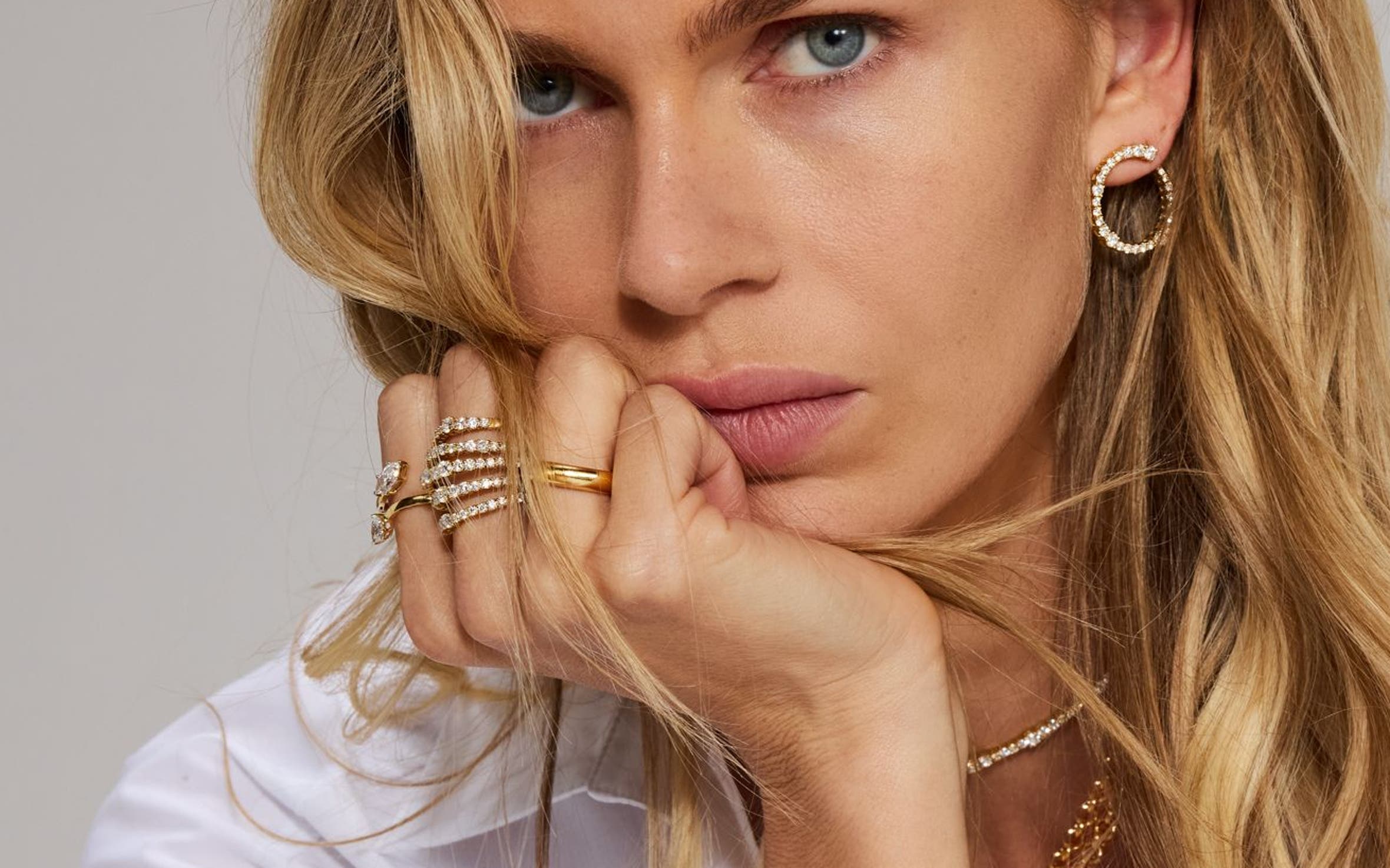 A woman wearing a variety of gold bracelets, rings, necklaces and earrings.