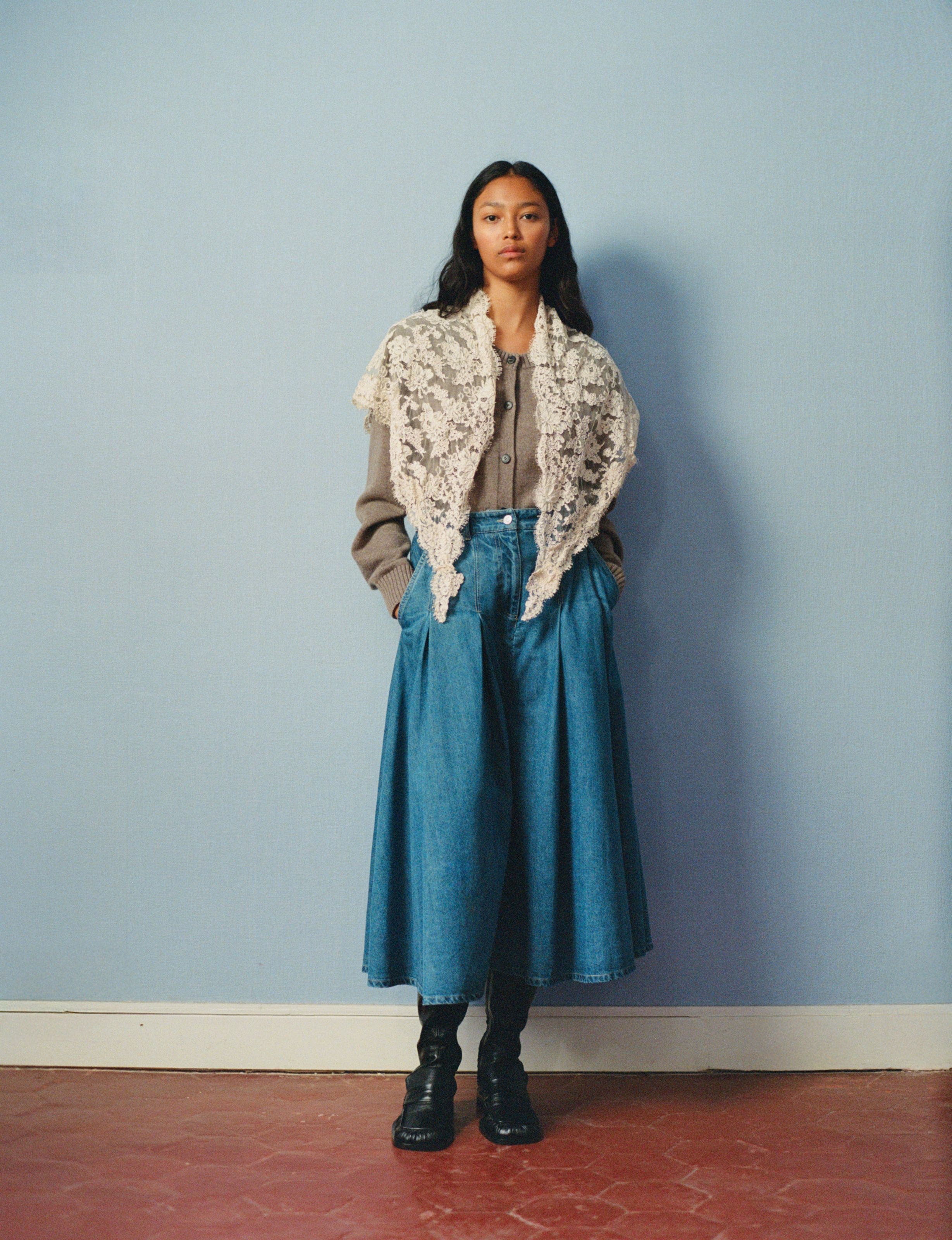 A woman wearing a denim maxi skirt and blouse, with a lace shawl.