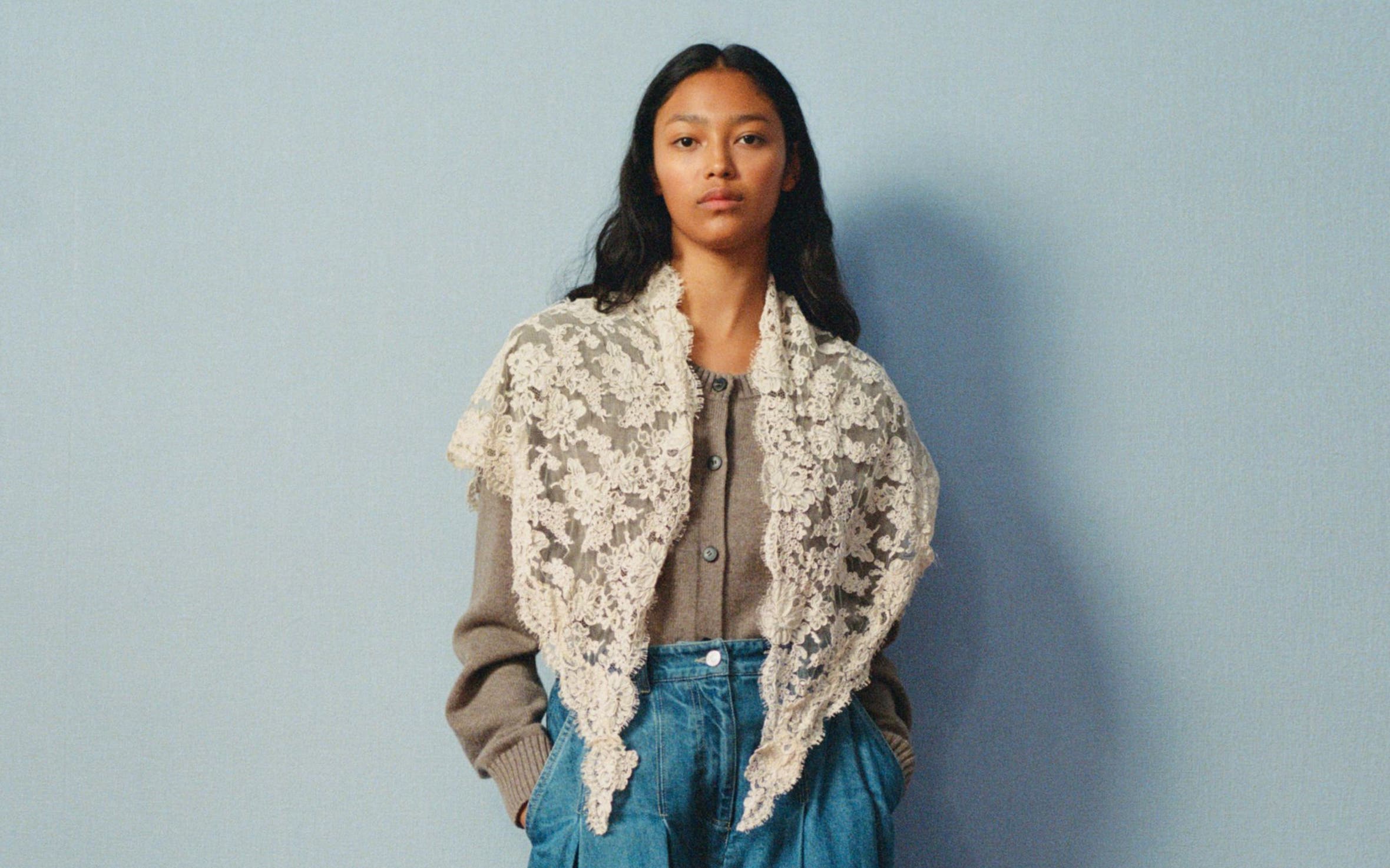 A woman wearing a denim maxi skirt and blouse, with a lace shawl.