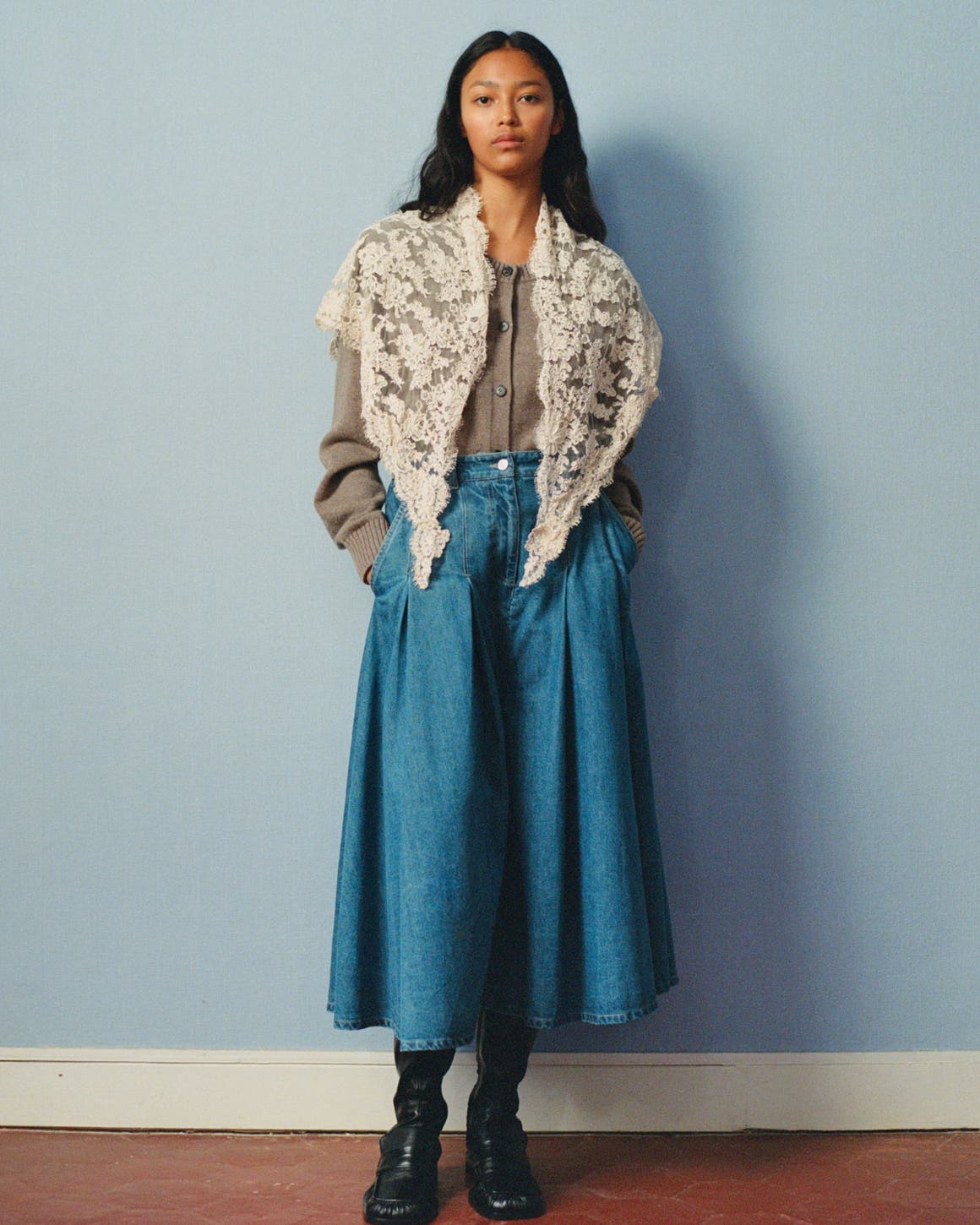 A woman wearing a denim maxi skirt and blouse, with a lace shawl.