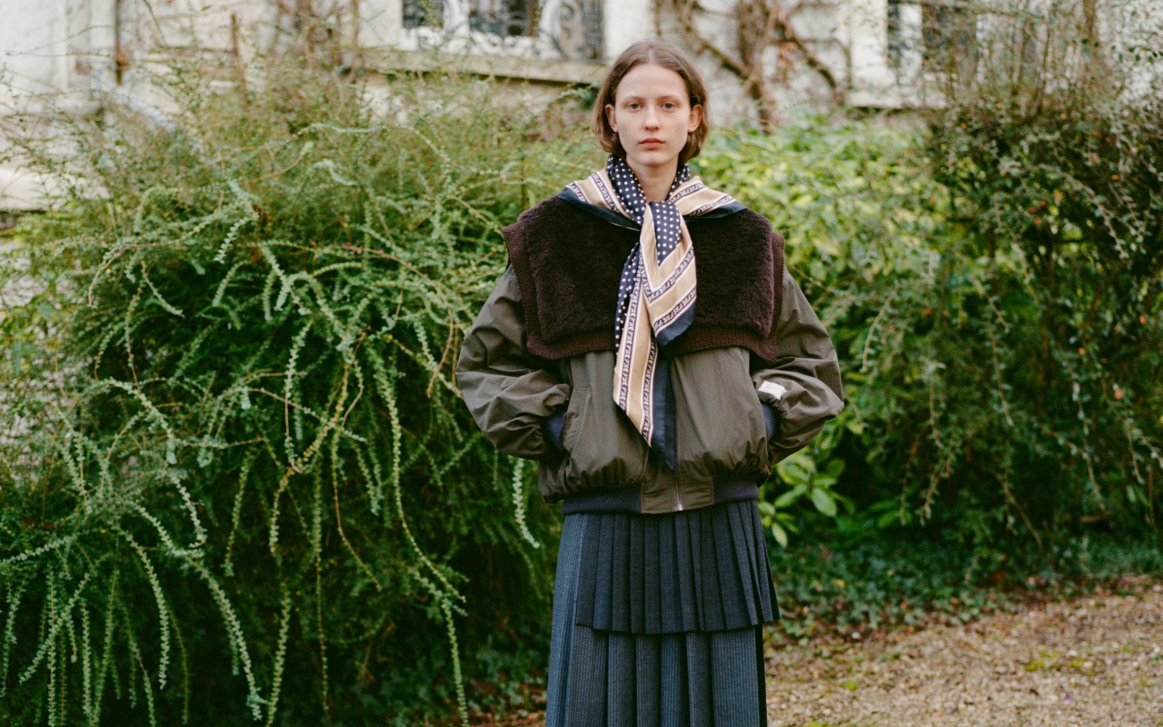 A woman wearing a coat and skirt.