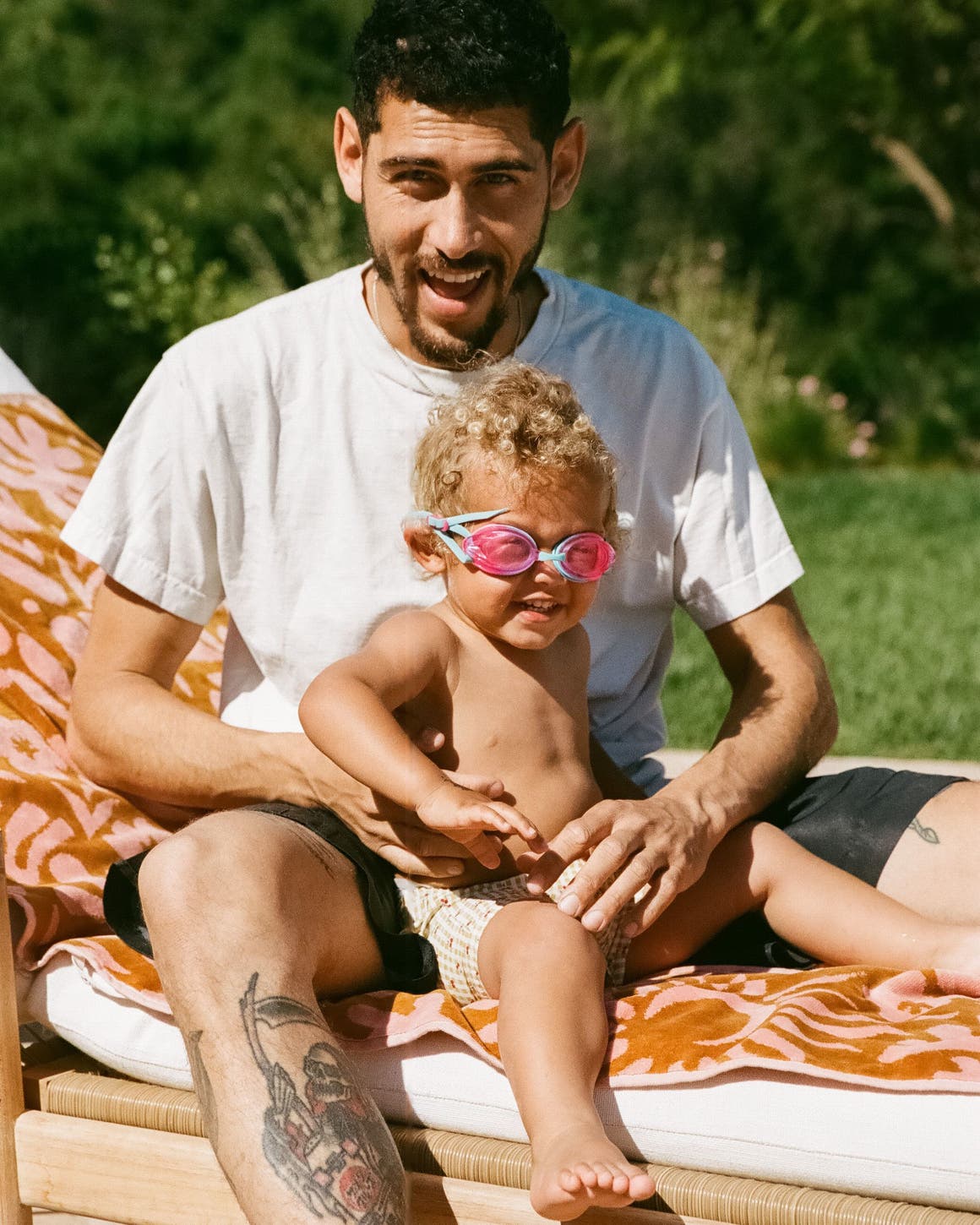 a man and a child sitting on a towel. 