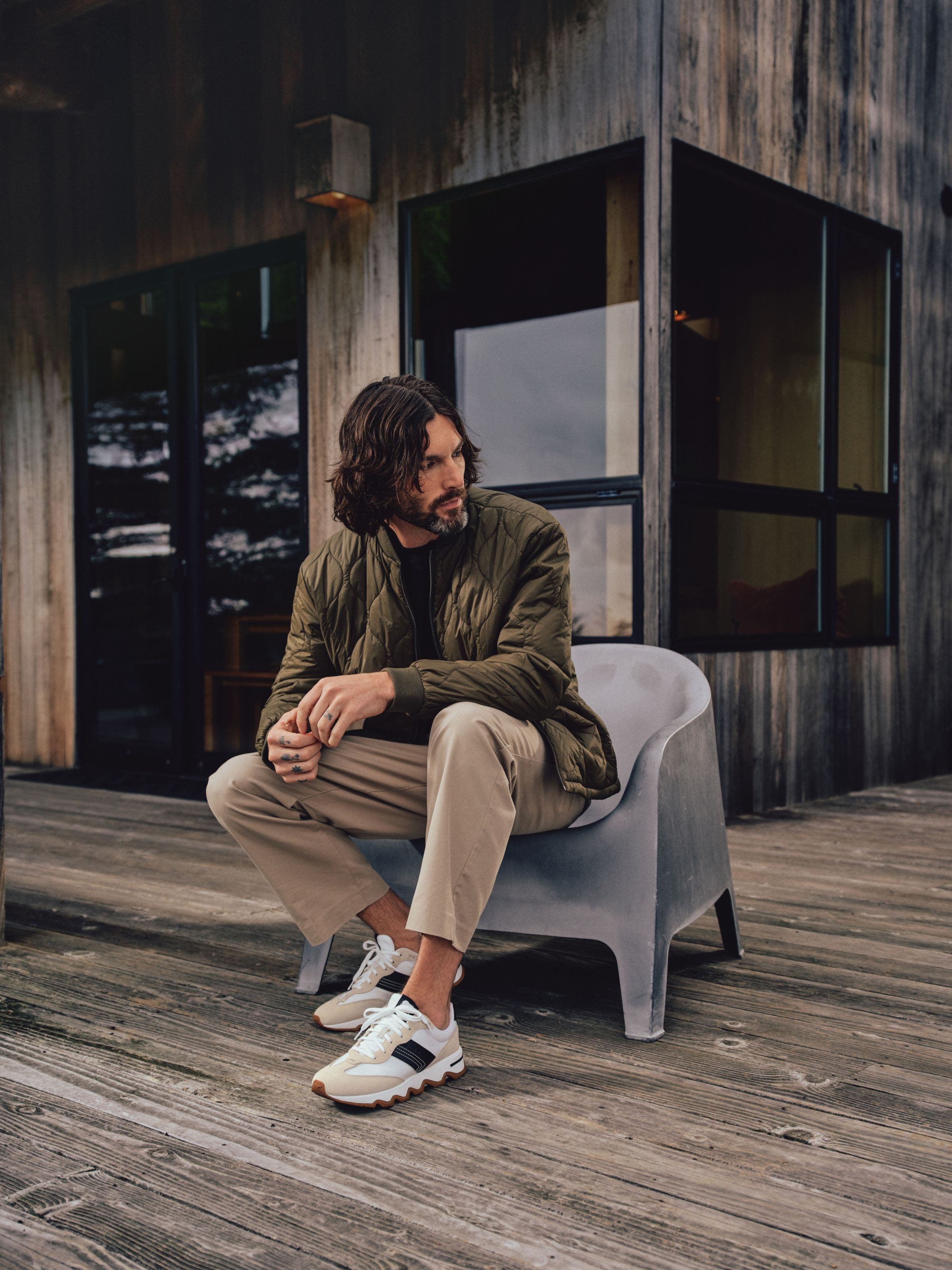 A man wearing a quilted jacket, pants and sneakers.