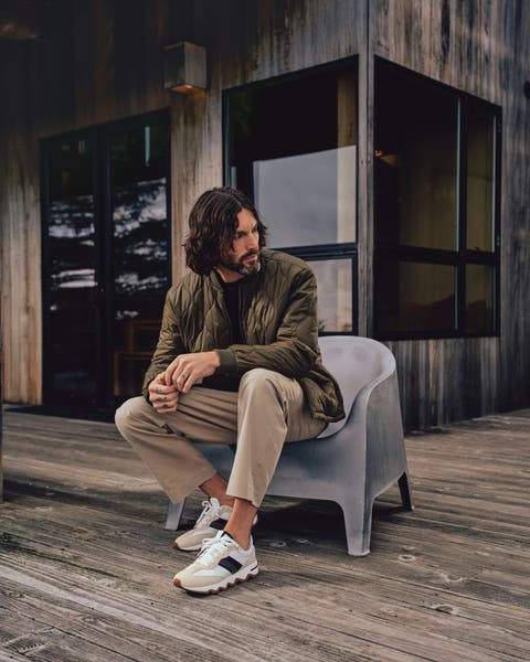 A man wearing a quilted jacket, pants and sneakers.