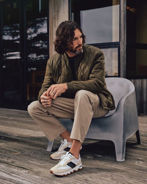 A man wearing a quilted jacket, pants and sneakers.