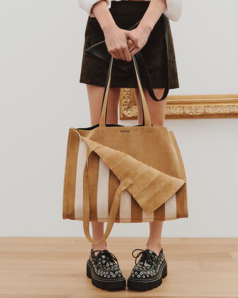 A women holding a stripe woven bag. 