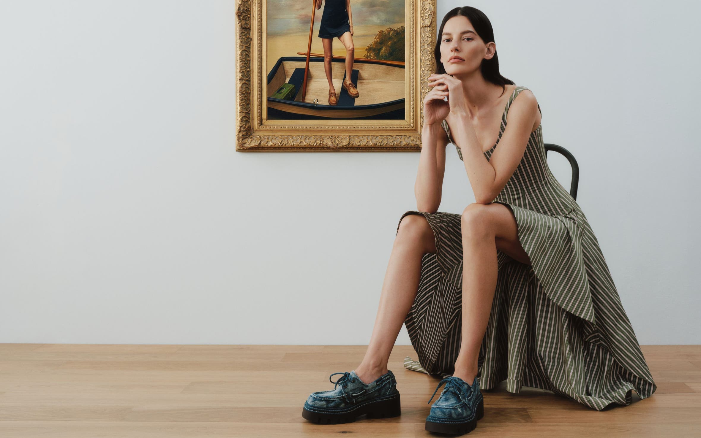 A woman in an art gallery wearing platform boat shoes with a striped dress.