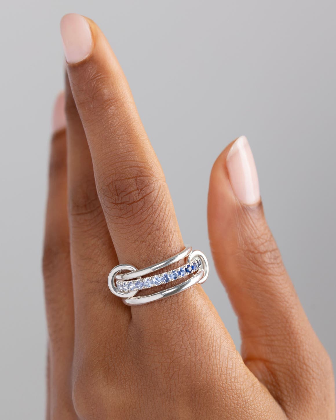 A woman wearing a silver and diamond Spinelli Kilcollin ring on her index finger.	