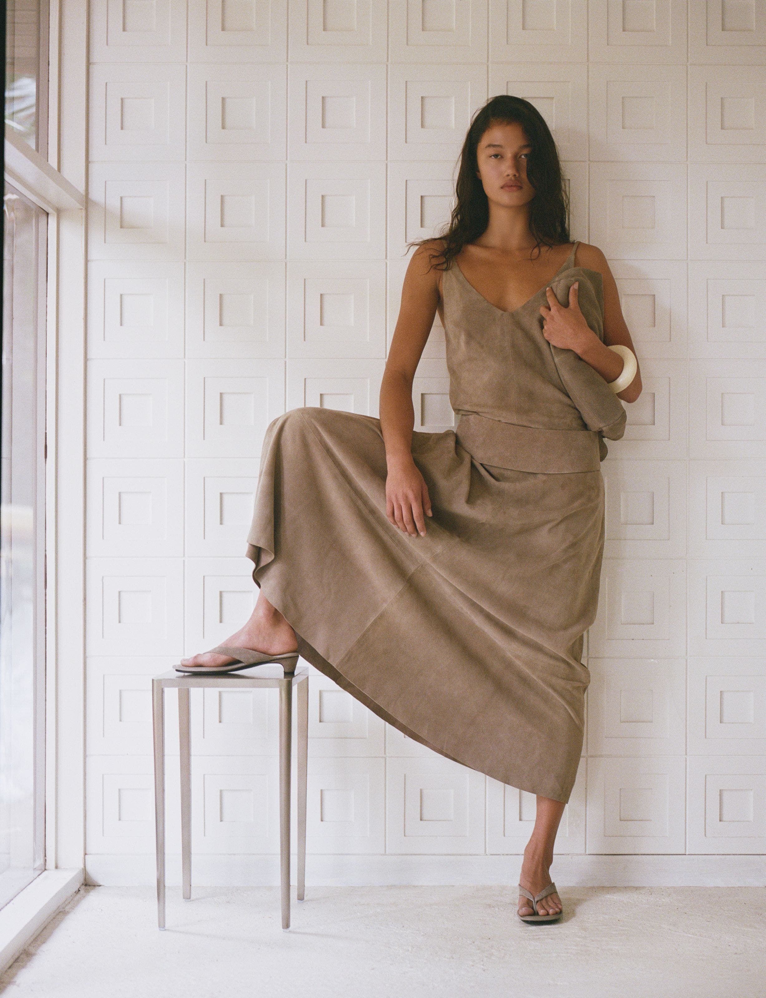 A woman wearing a suede top and matching skirt.